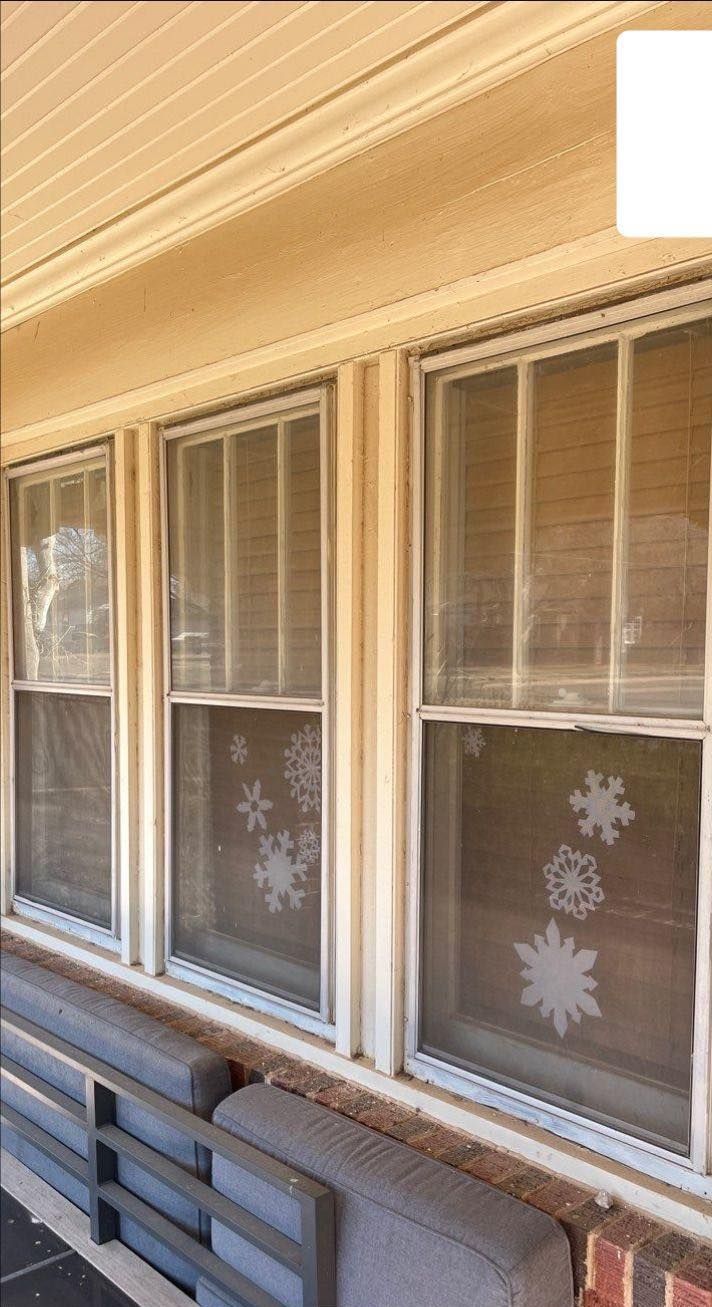 A row of windows on a porch with snowflakes painted on them.