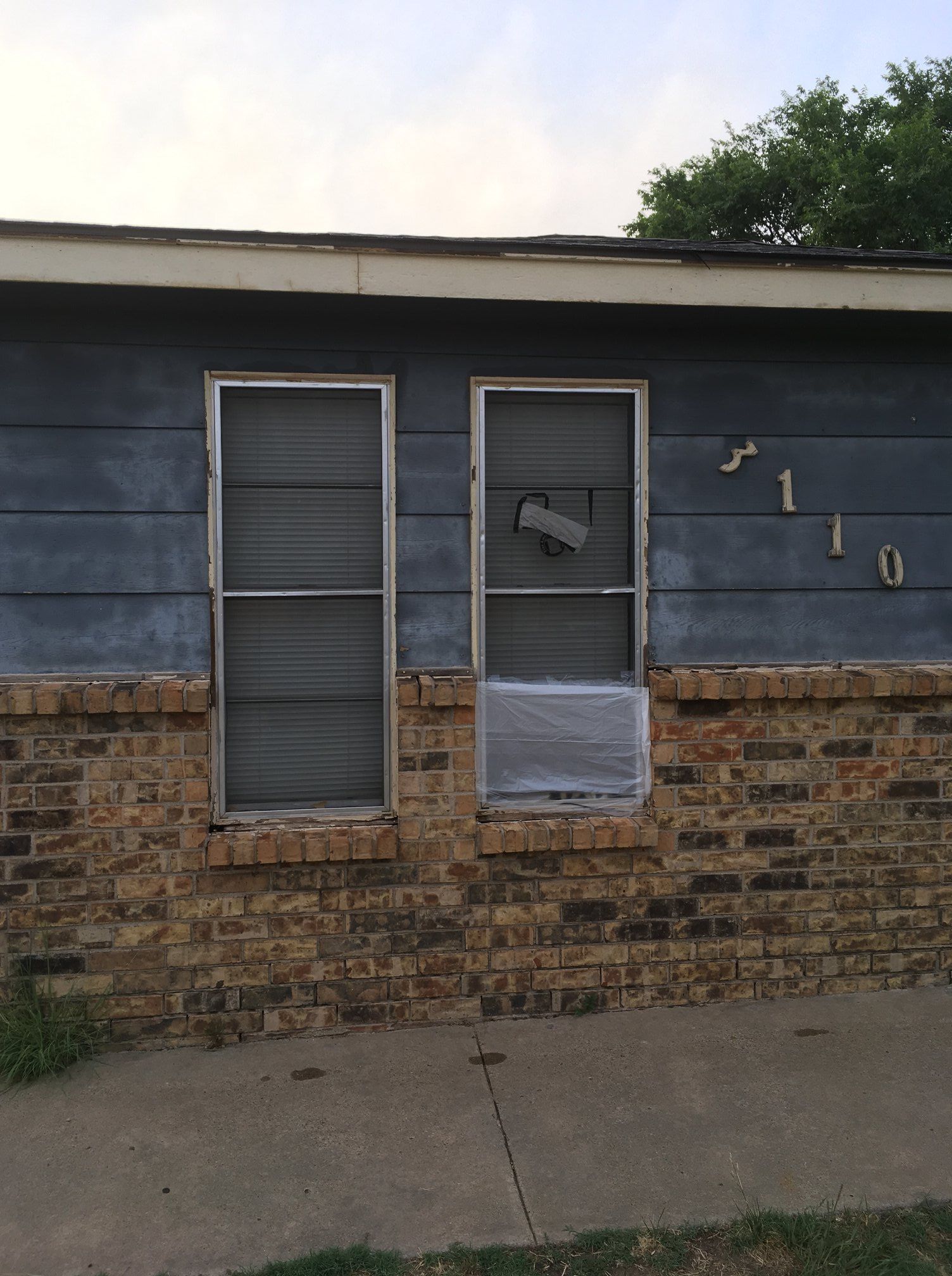 A house with a broken window and a brick wall.