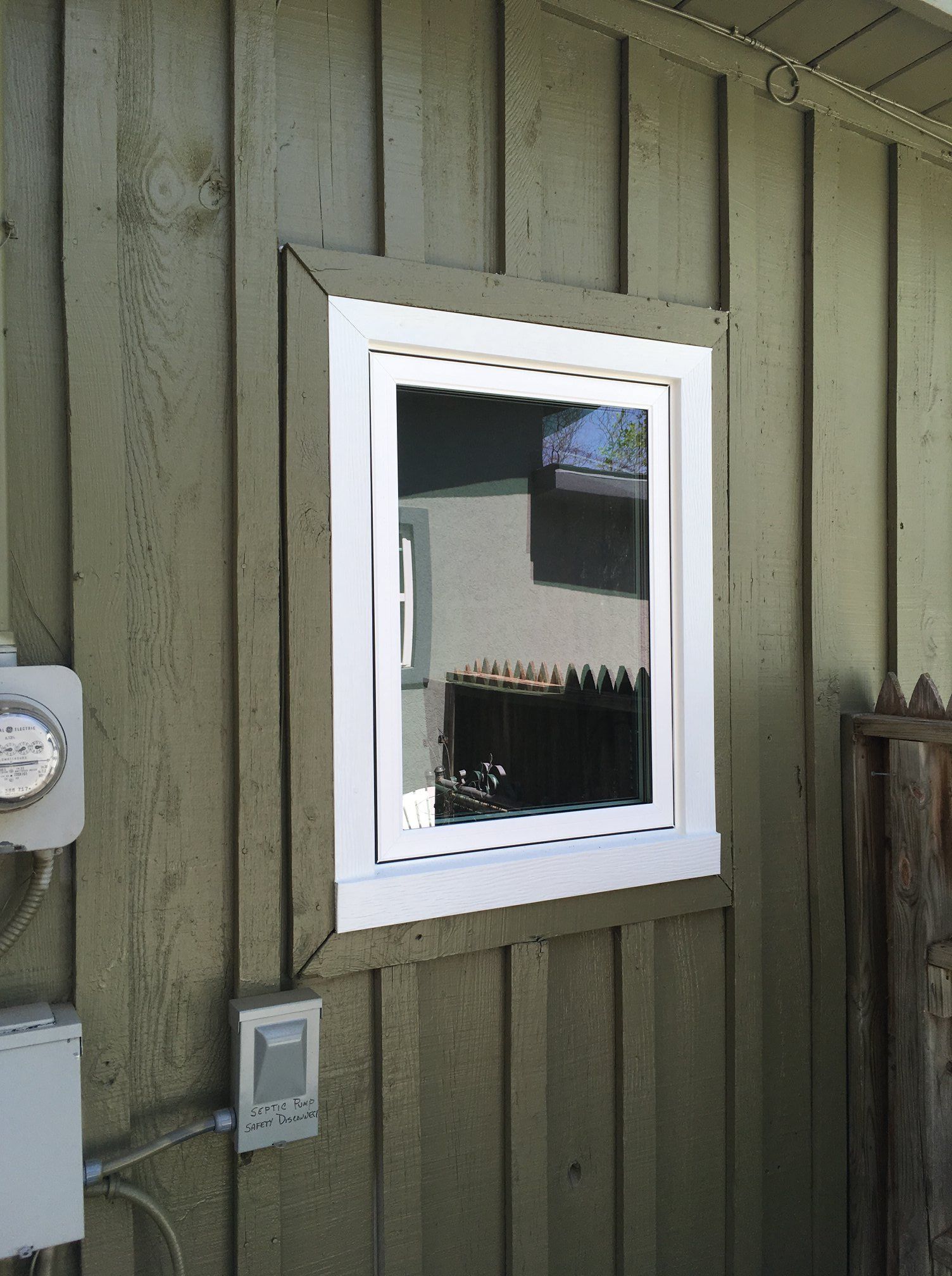 A window on the side of a house with a white frame.