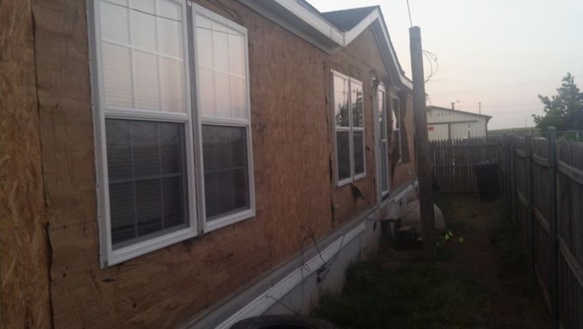 A mobile home with a lot of windows and a fence in the backyard.