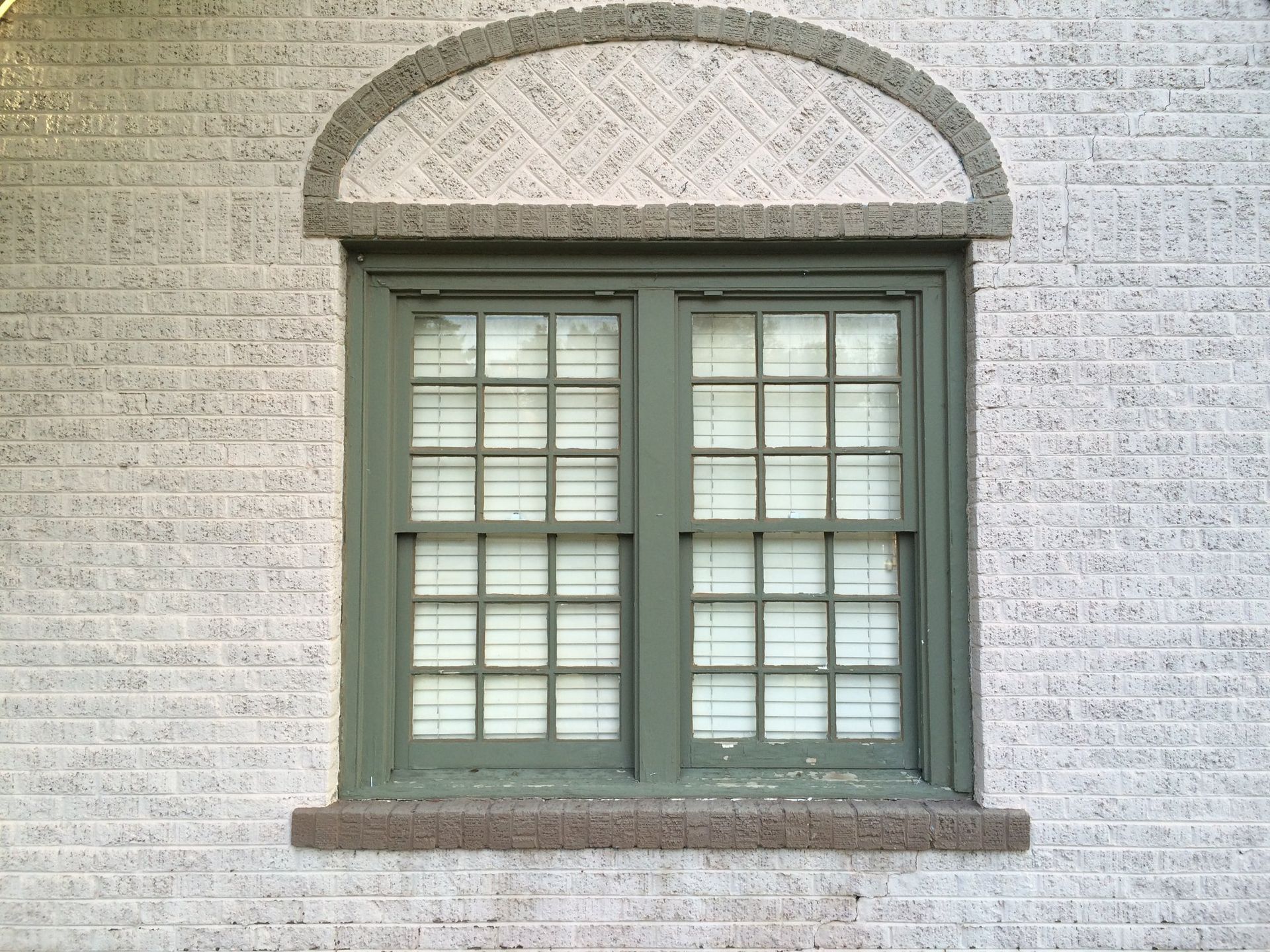 A green window on a white brick wall