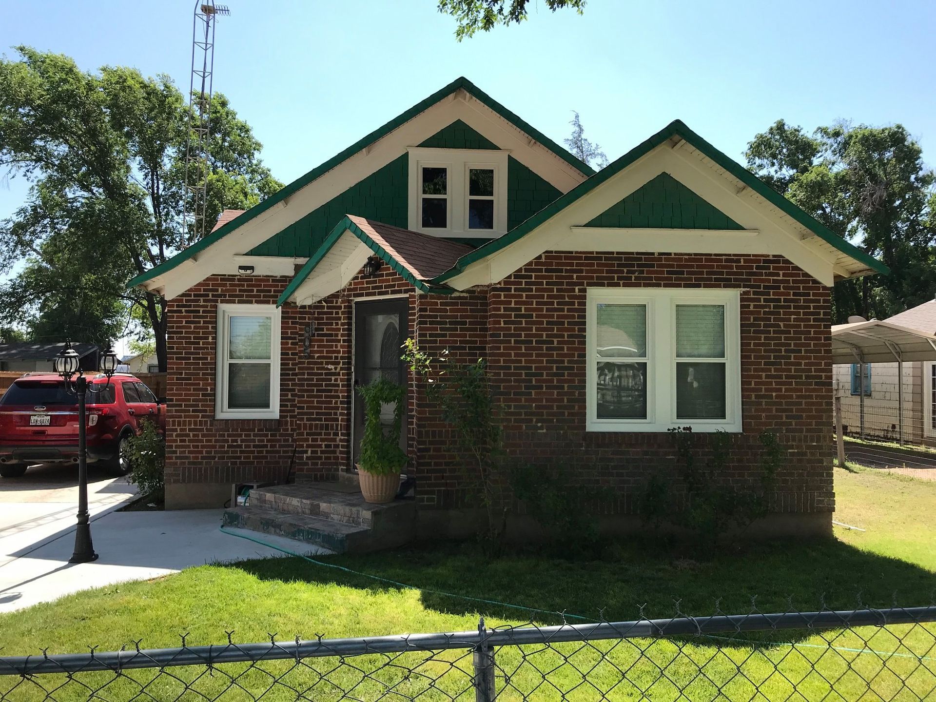 A brick house with a green roof and white trim