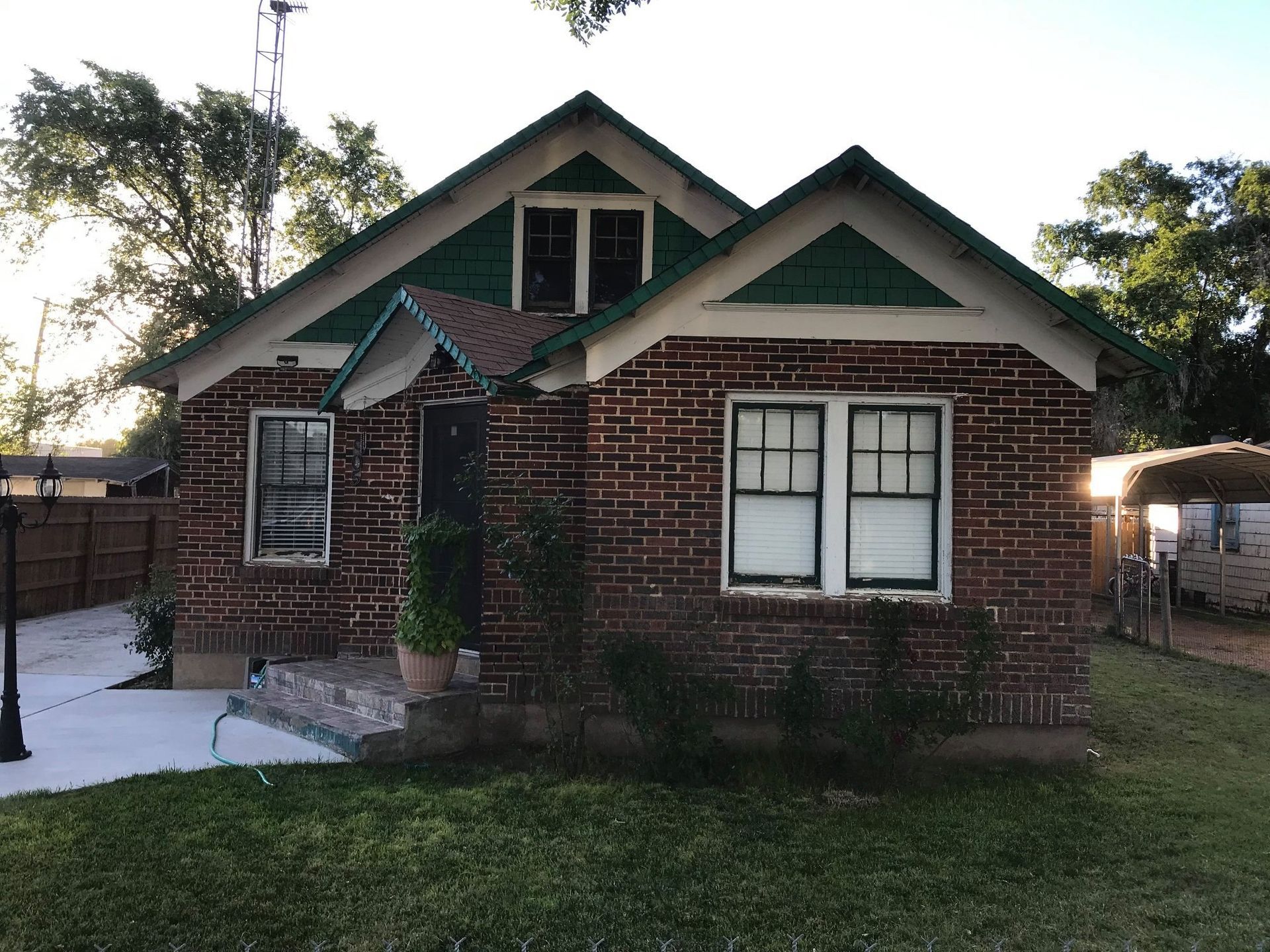 A brick house with a green roof and white trim