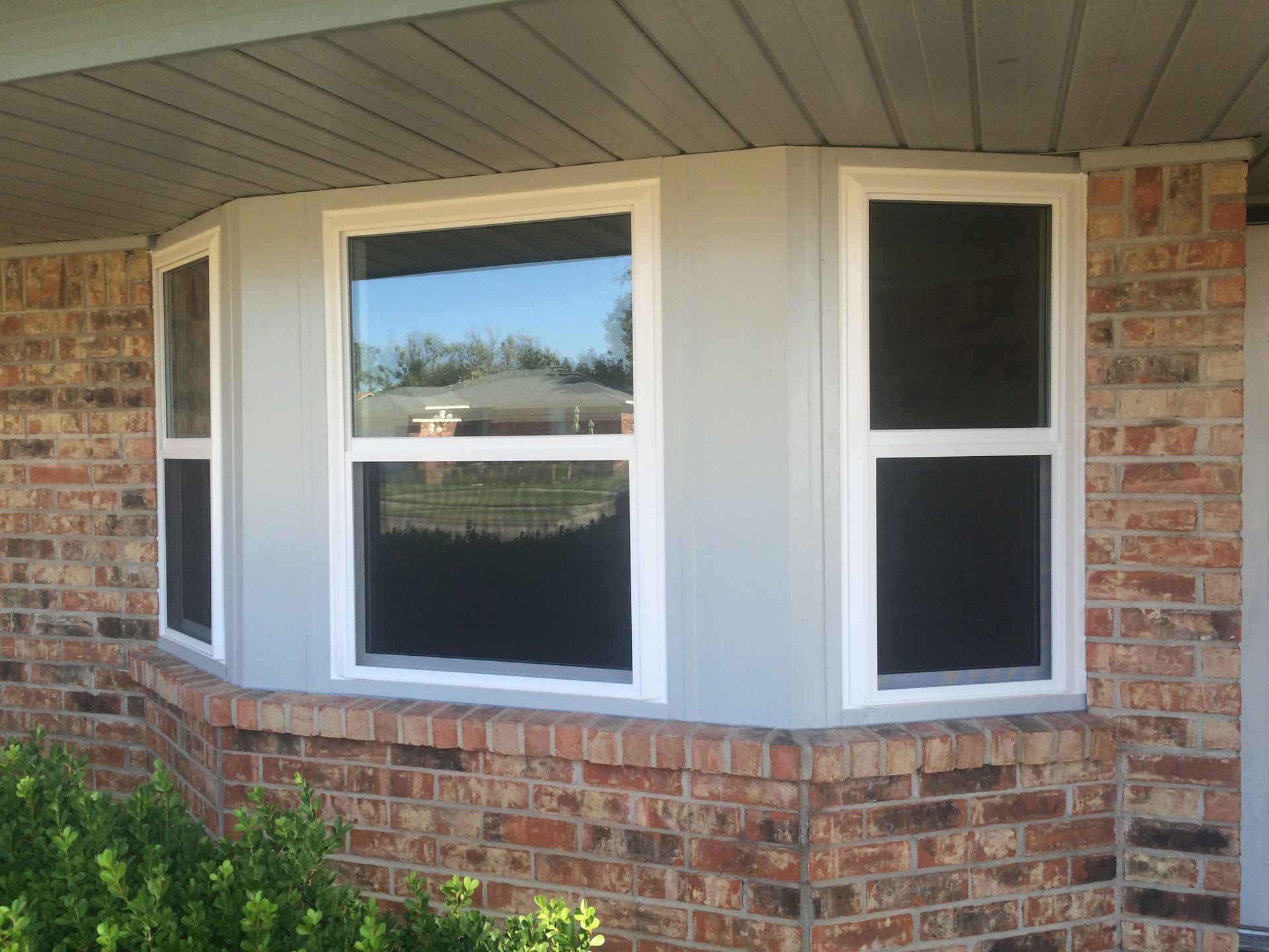 A brick house with two windows on the side of it.