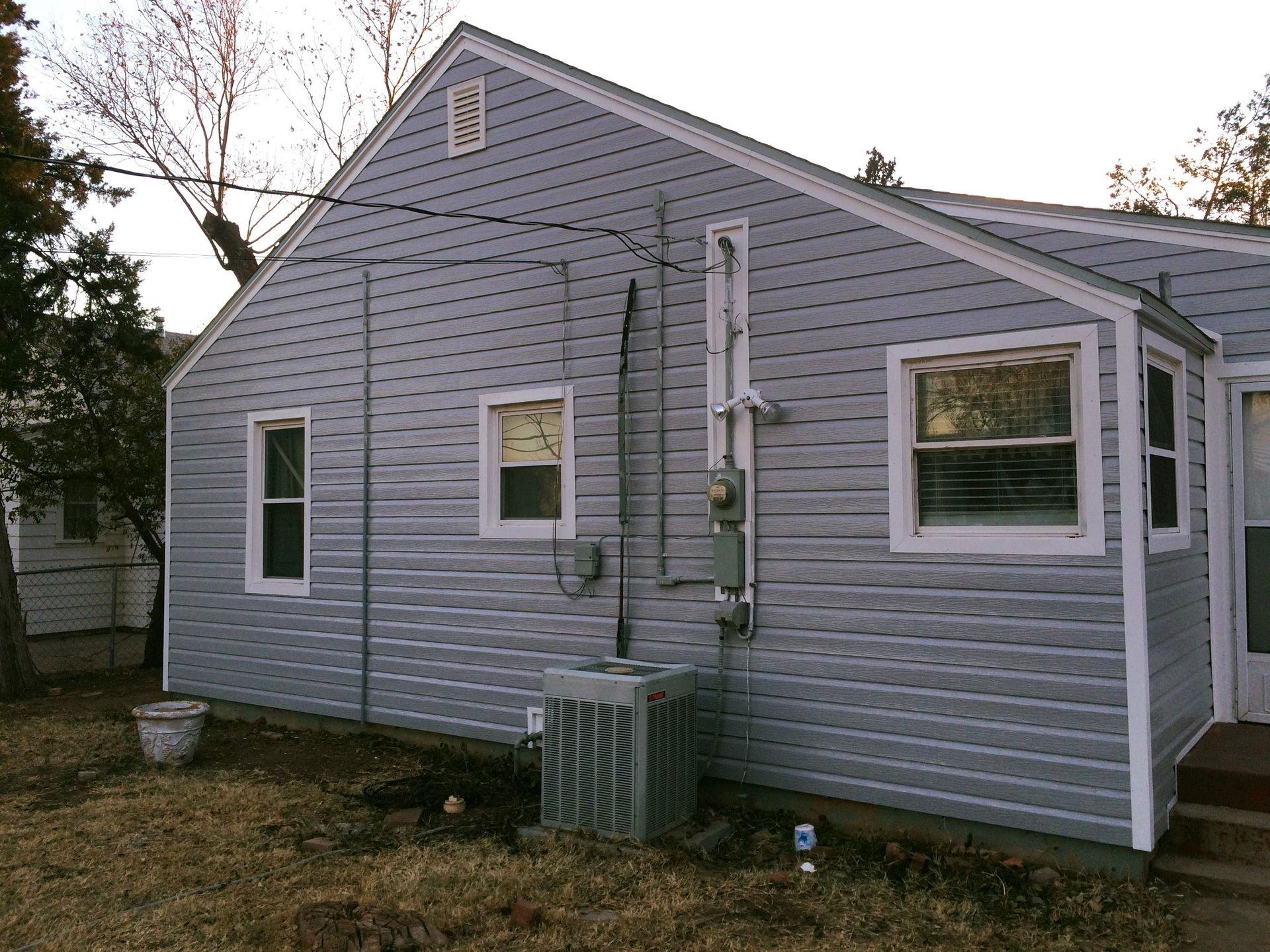 The back of a house with a gray siding and white trim