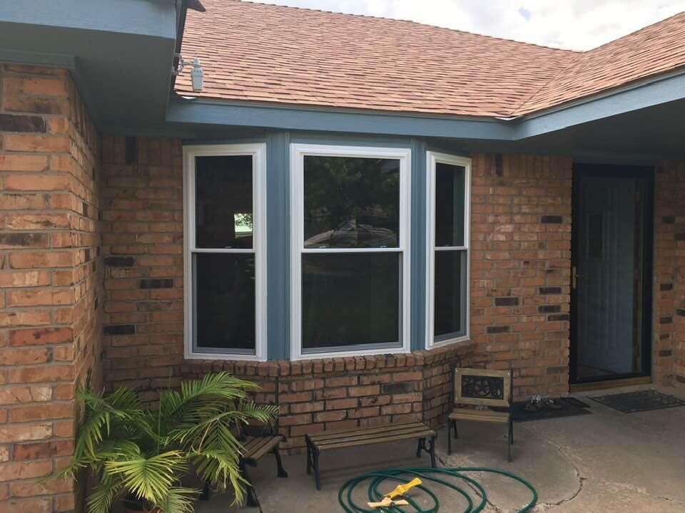 A brick house with a large bay window and a hose in front of it.