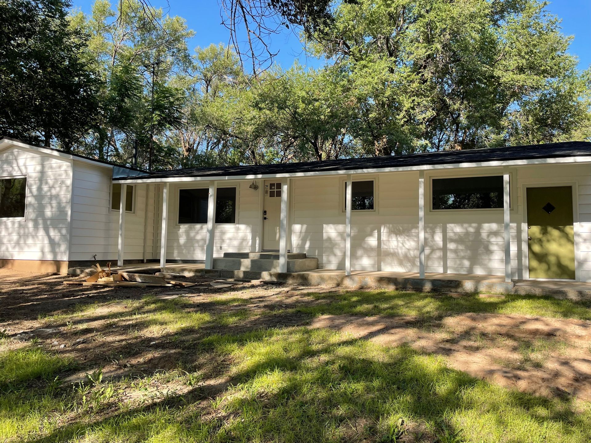 A white house with a porch and trees in the background.