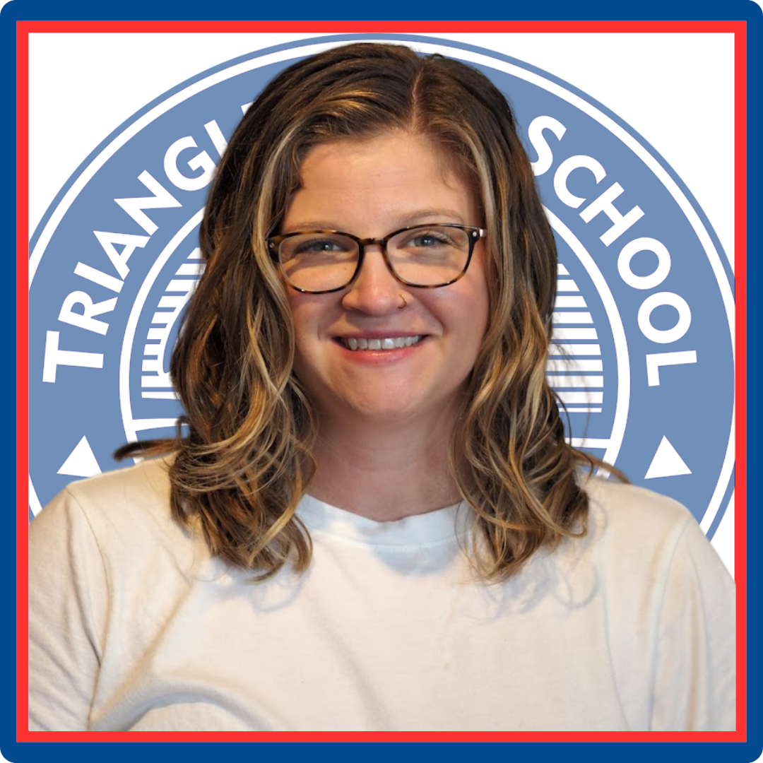 A woman wearing glasses is smiling in front of a triangle school logo