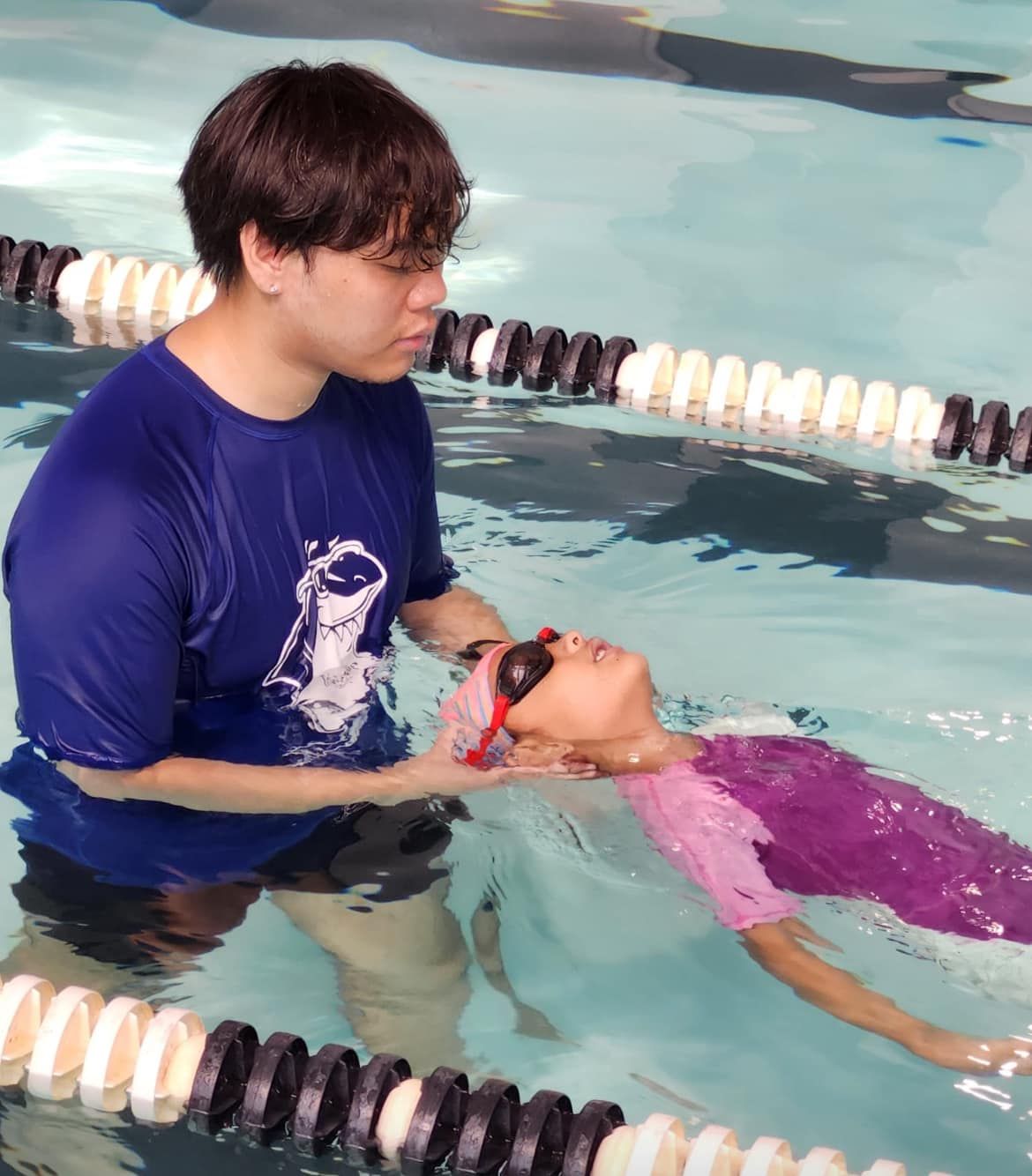 A man is helping a young girl swim in a pool