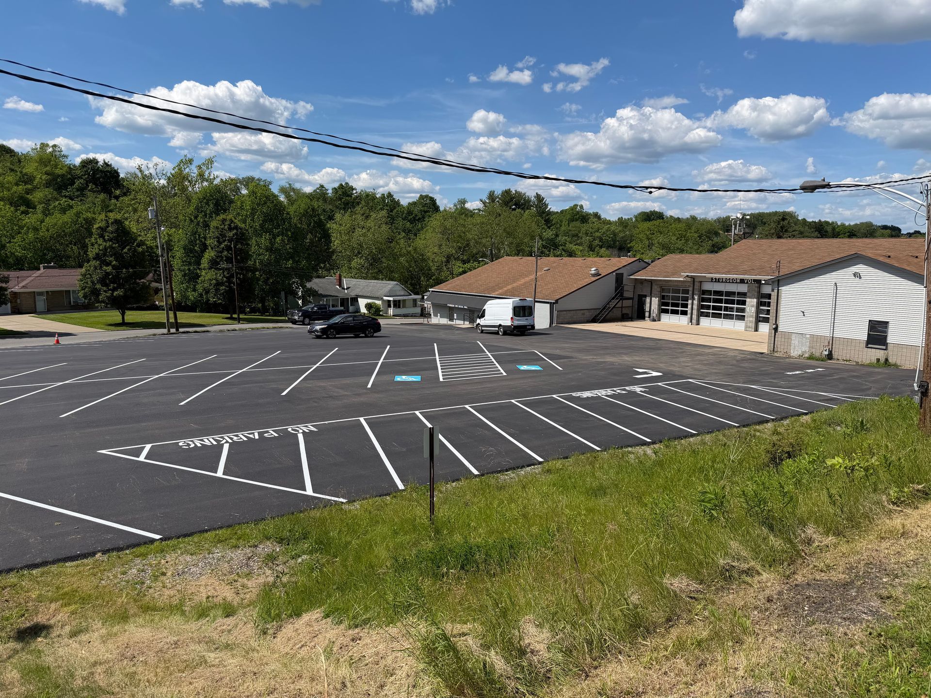 Empty parking lot beside a building under a blue sky with scattered clouds
