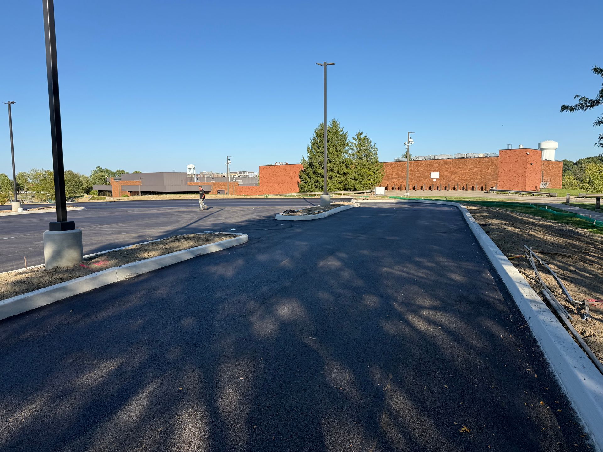 Freshly paved parking lot leading to a brick building under a clear blue sky