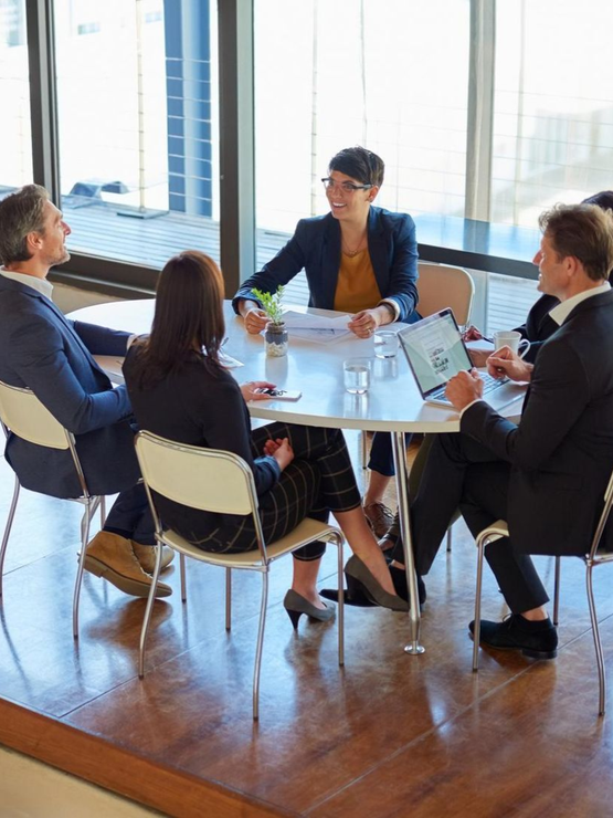 Business meeting around a round table in a bright office with laptops and papers