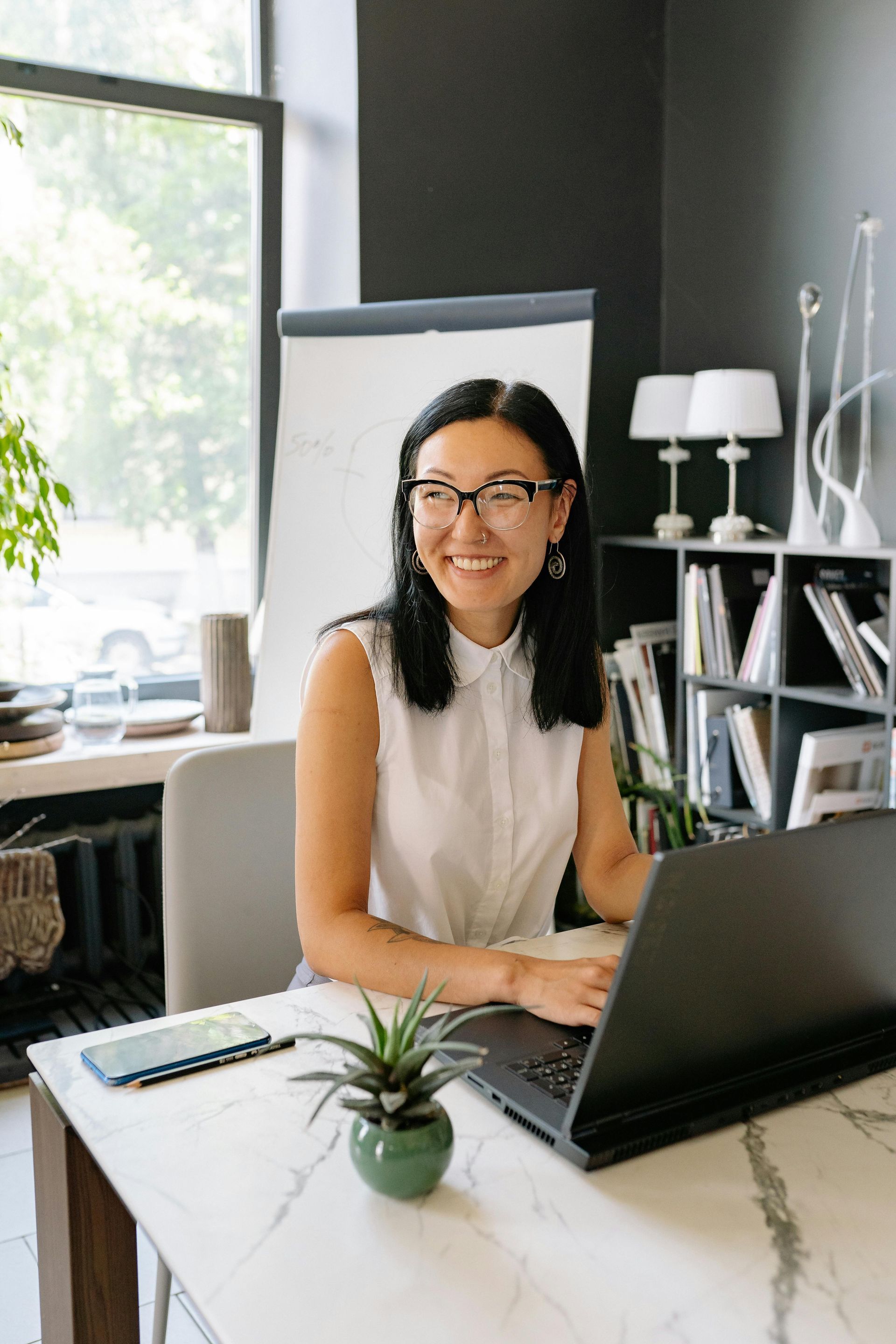 A woman is sitting at a desk in front of a laptop computer.