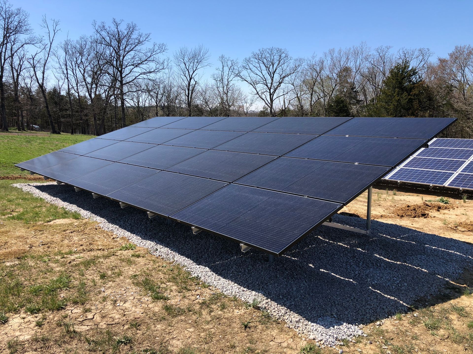 A row of solar panels sitting on top of a dirt field.