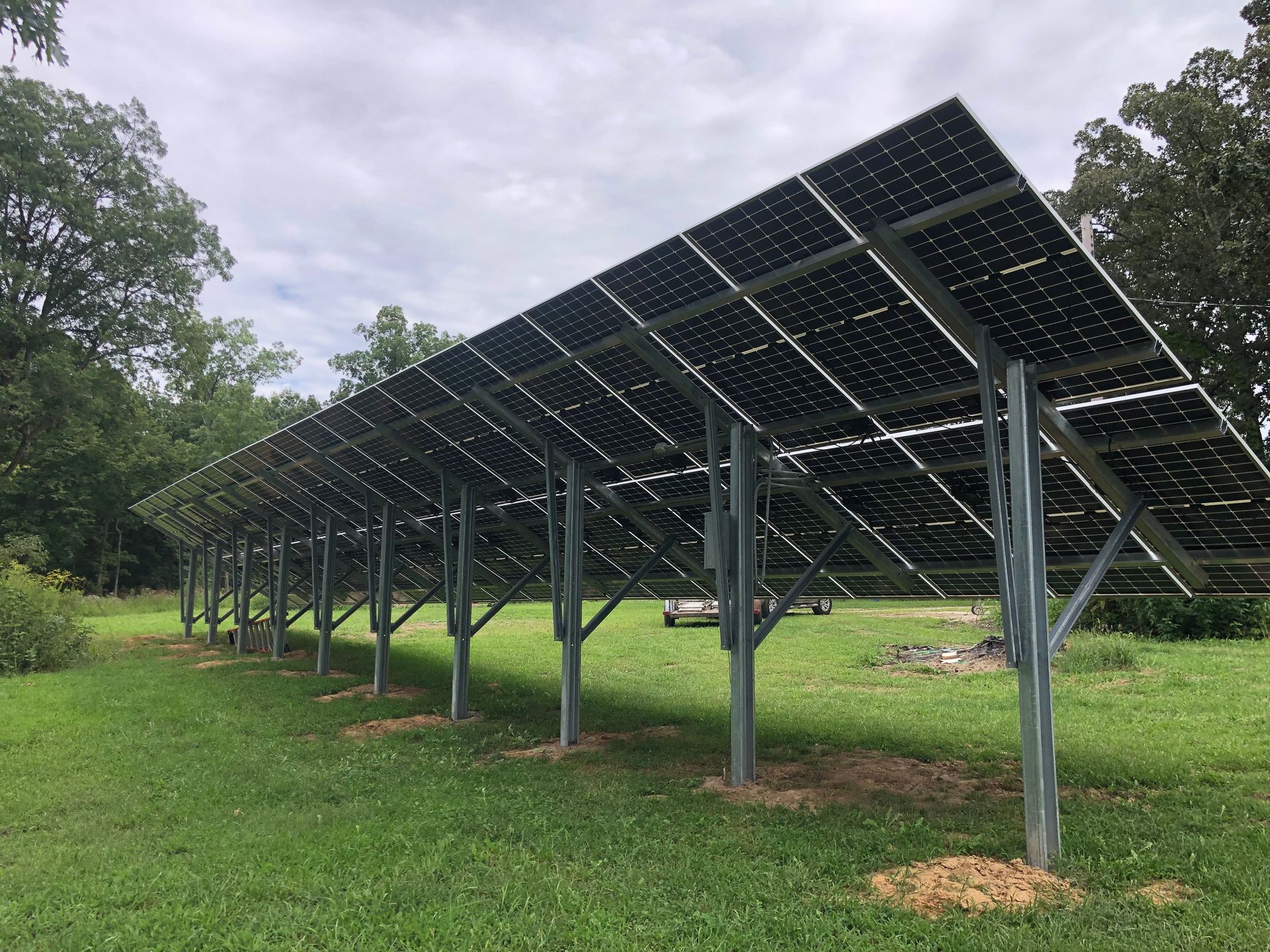 A row of solar panels are sitting in a grassy field.
