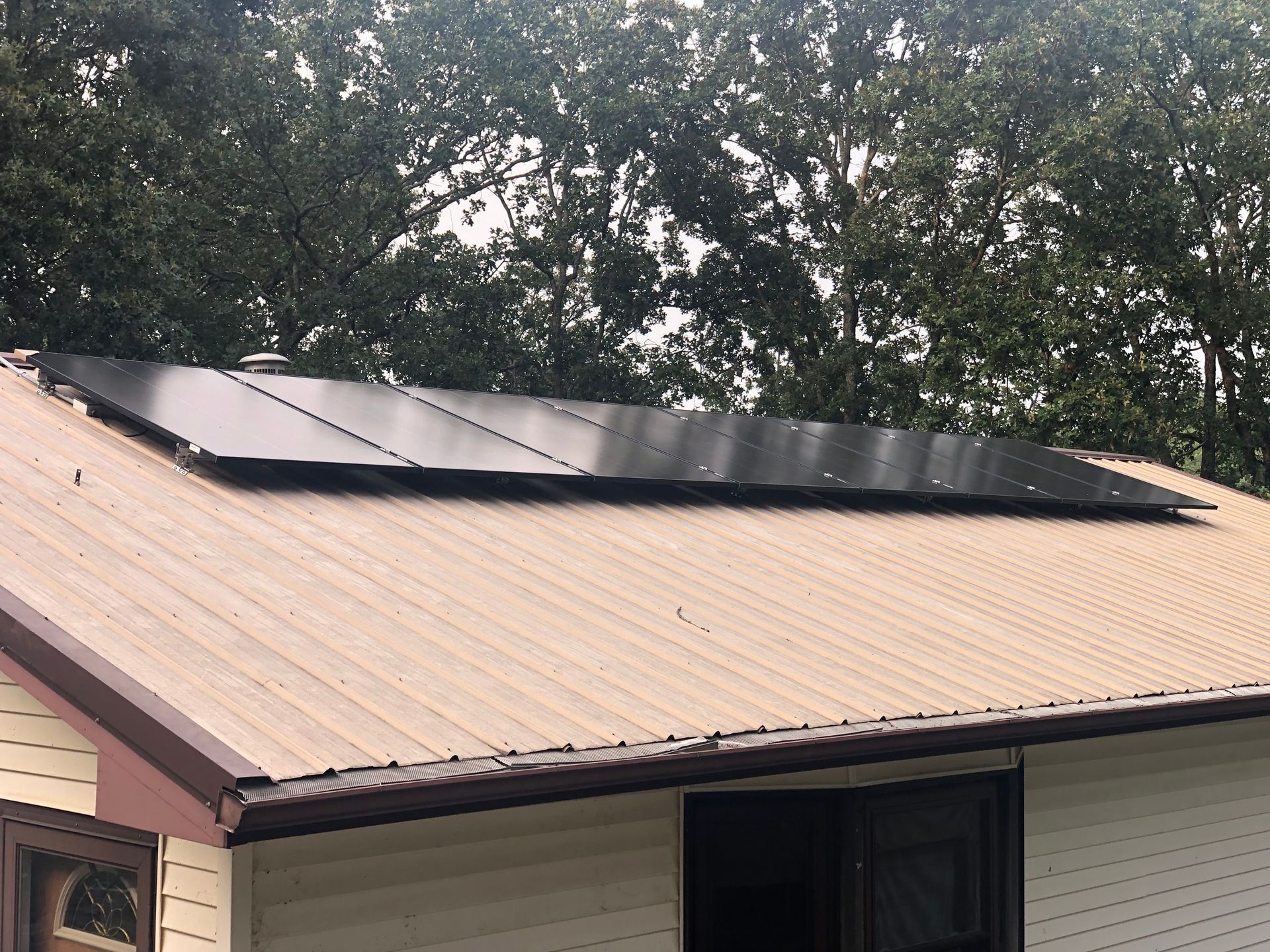 A house with solar panels on the roof and trees in the background.