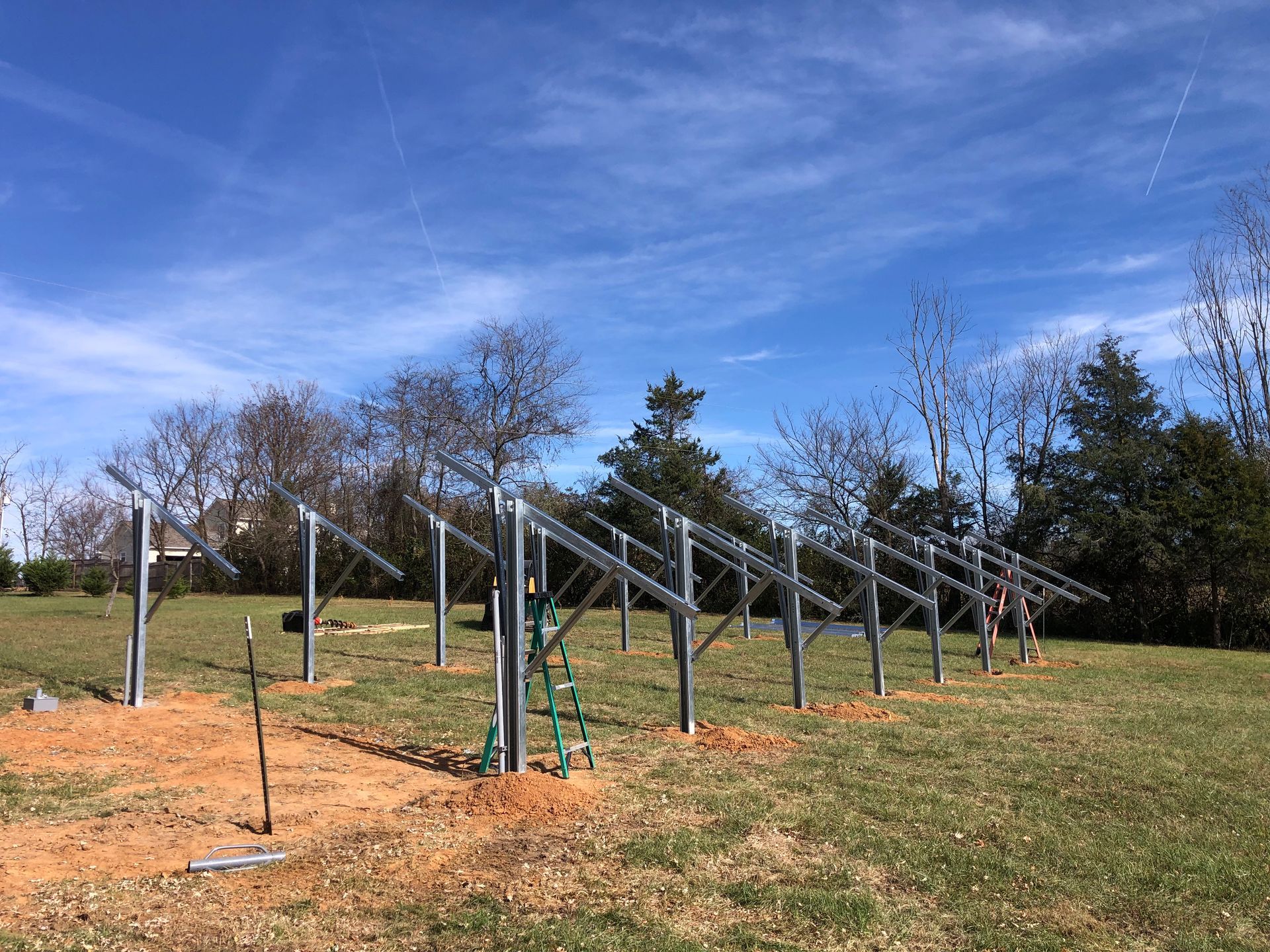 A row of solar panels are sitting in the middle of a grassy field.