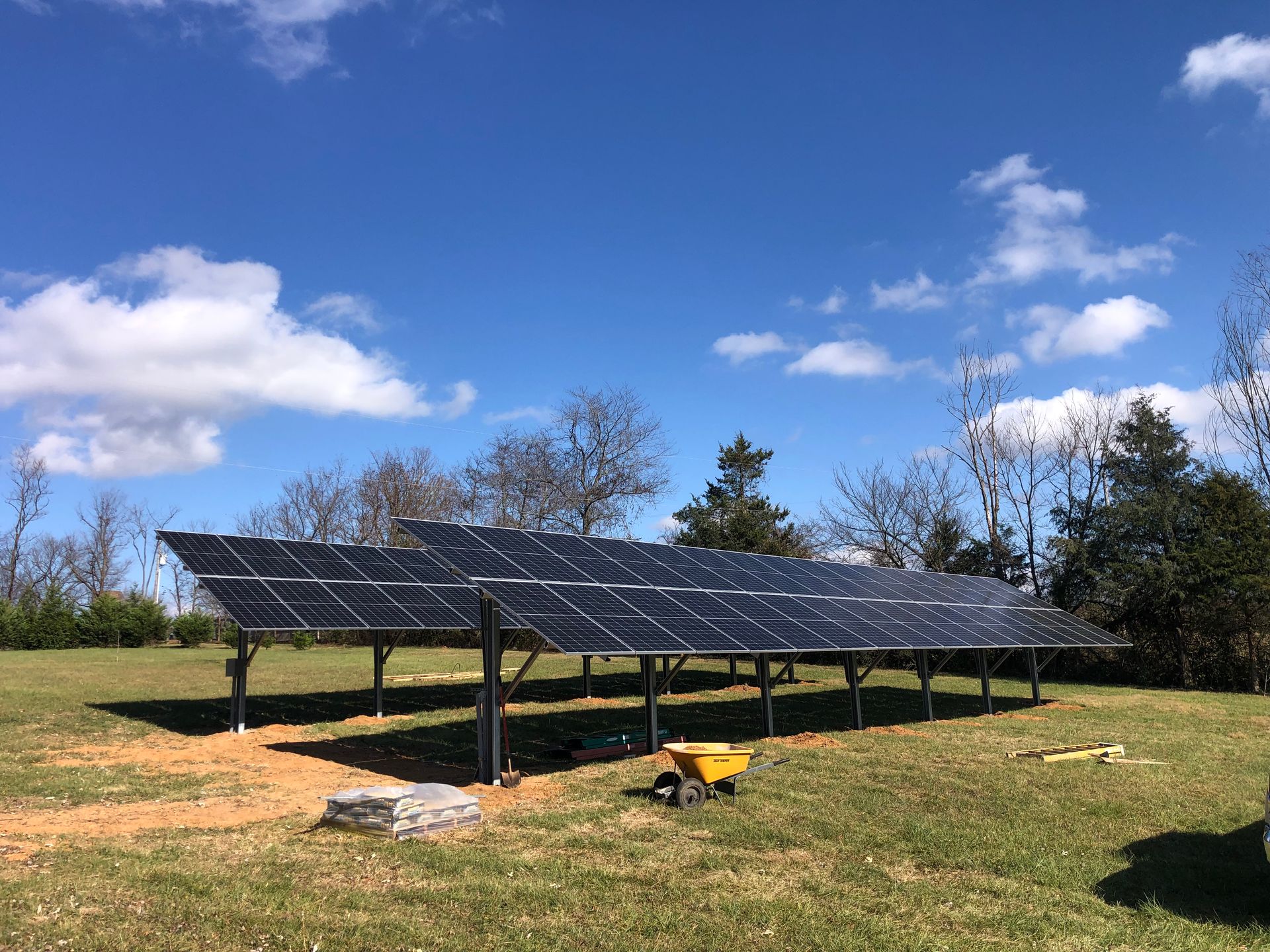 A row of solar panels sitting on top of a lush green field.