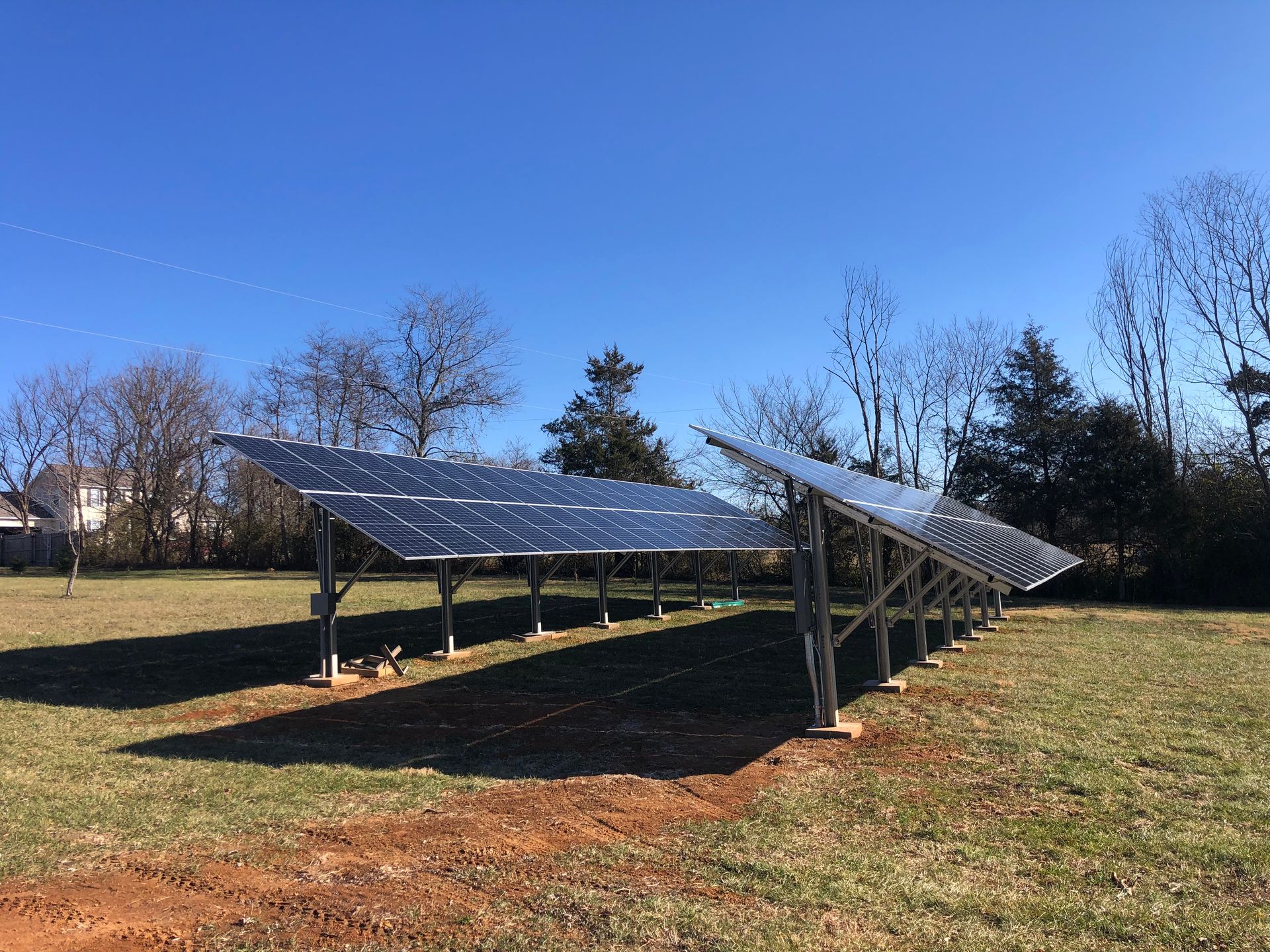 A row of solar panels sitting on top of a grassy field.