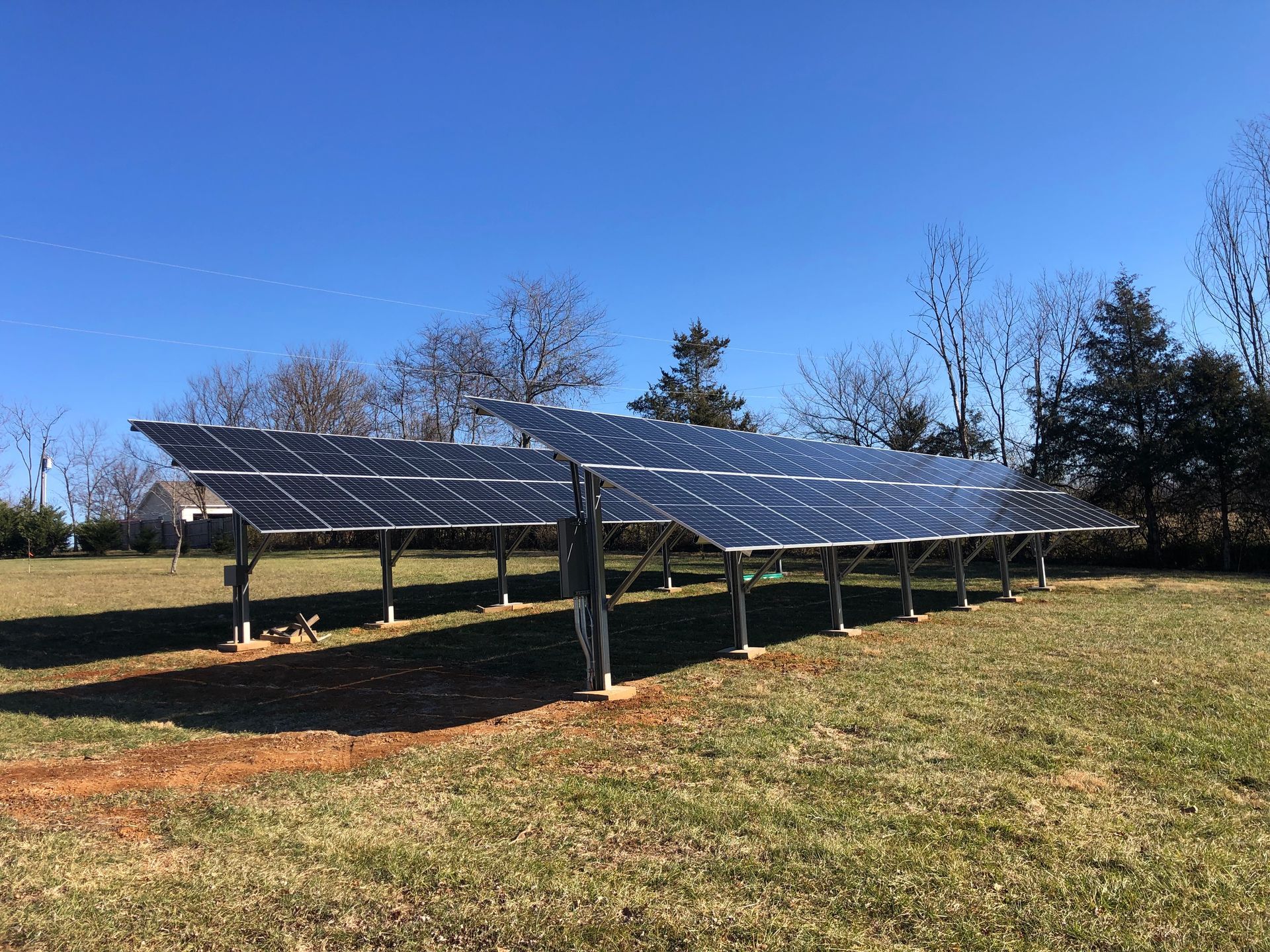 A row of solar panels are sitting in a grassy field.