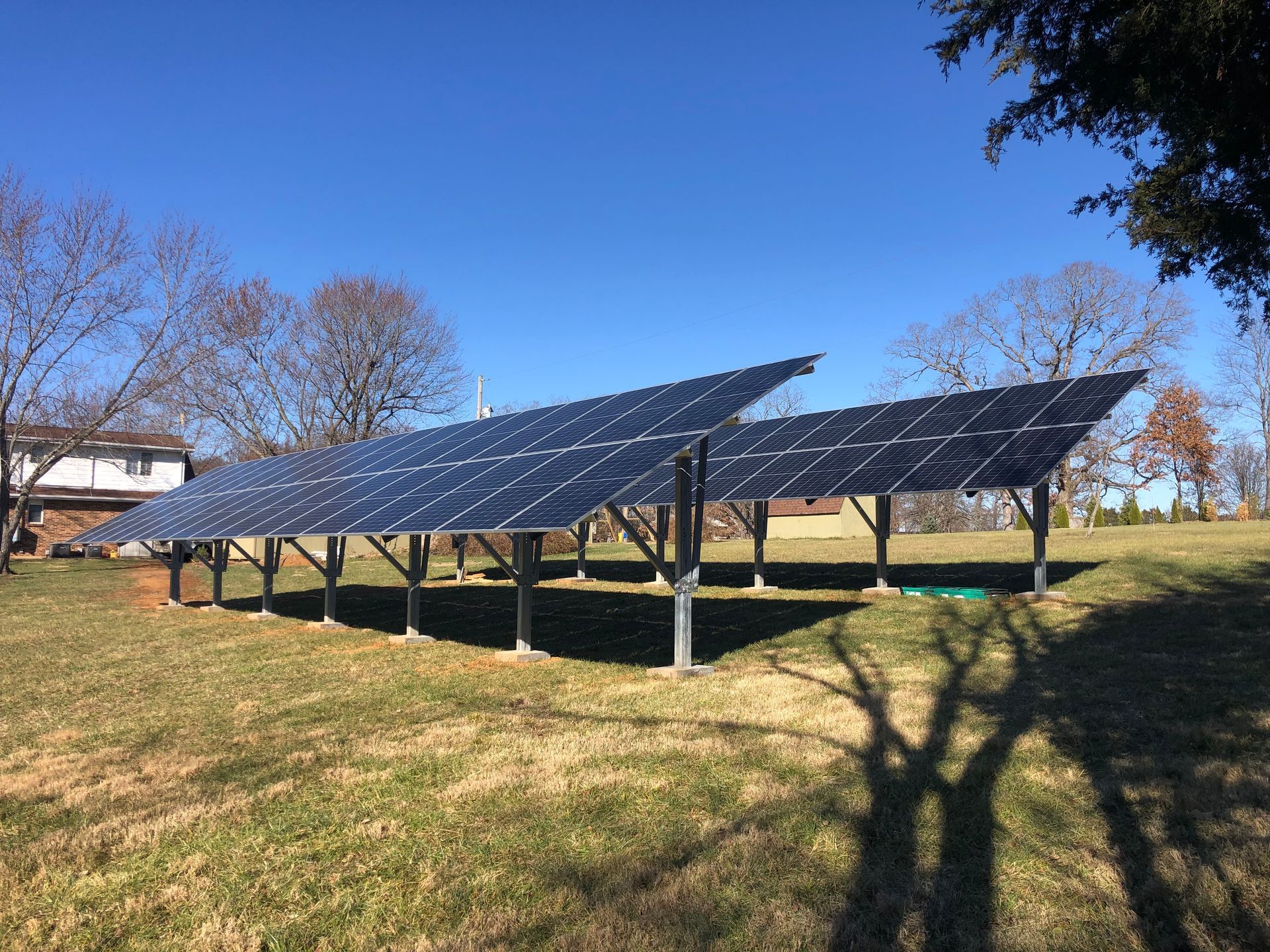A row of solar panels are sitting in a grassy field.