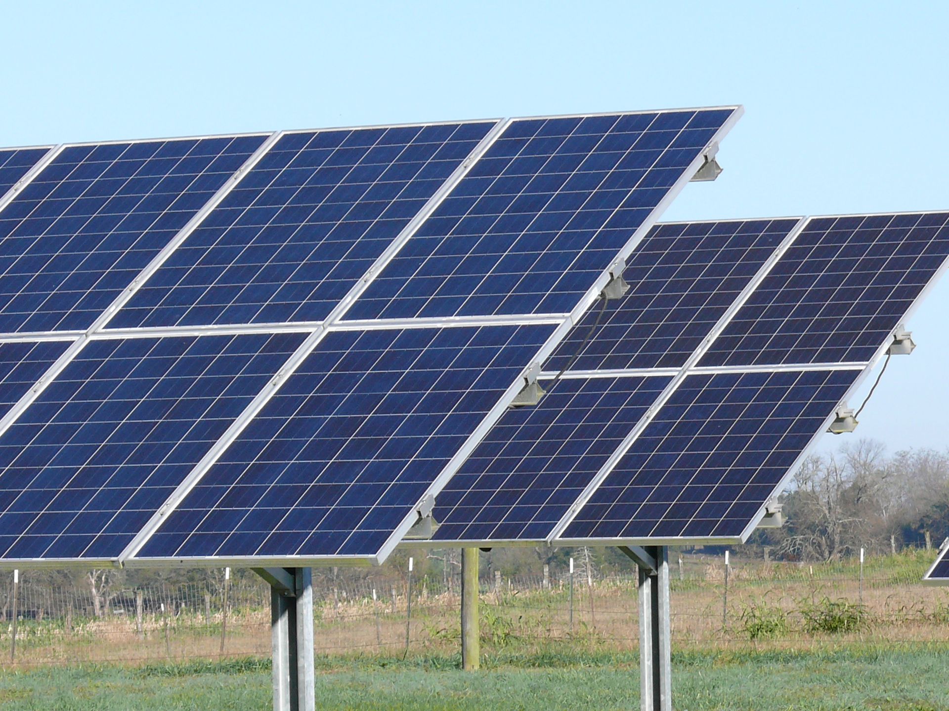 A row of solar panels in a field with a blue sky in the background