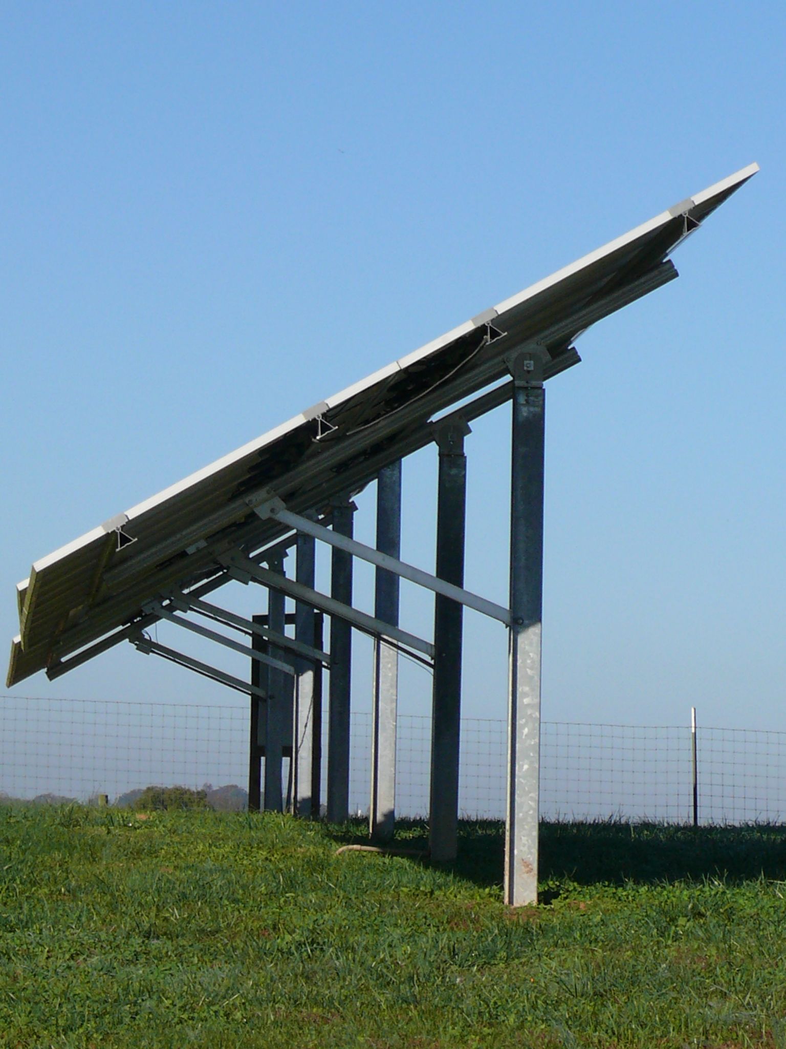 A row of solar panels sitting on top of a grassy hill