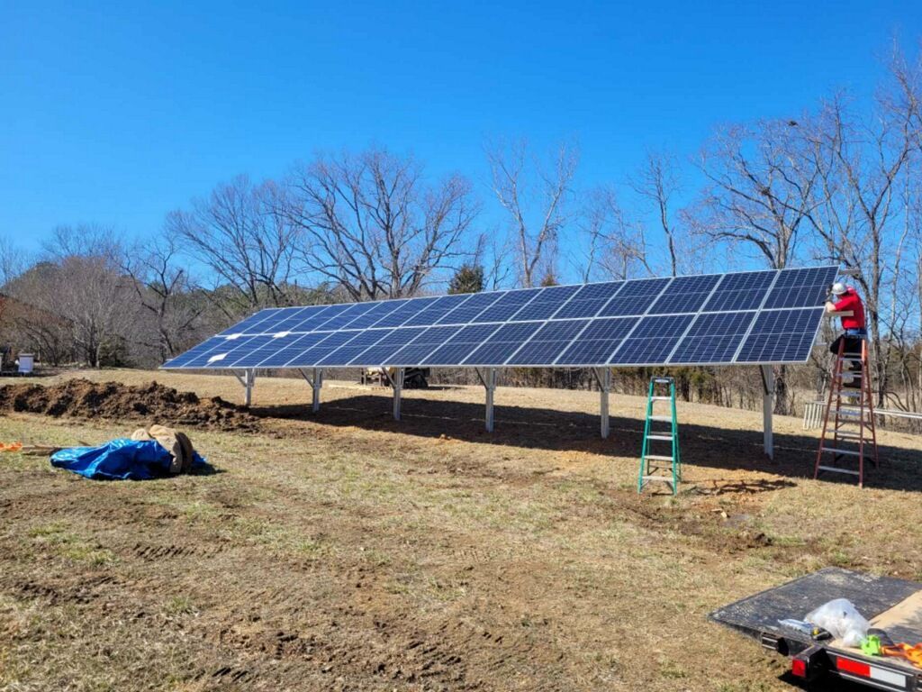 A man is working on a solar panel in a field.