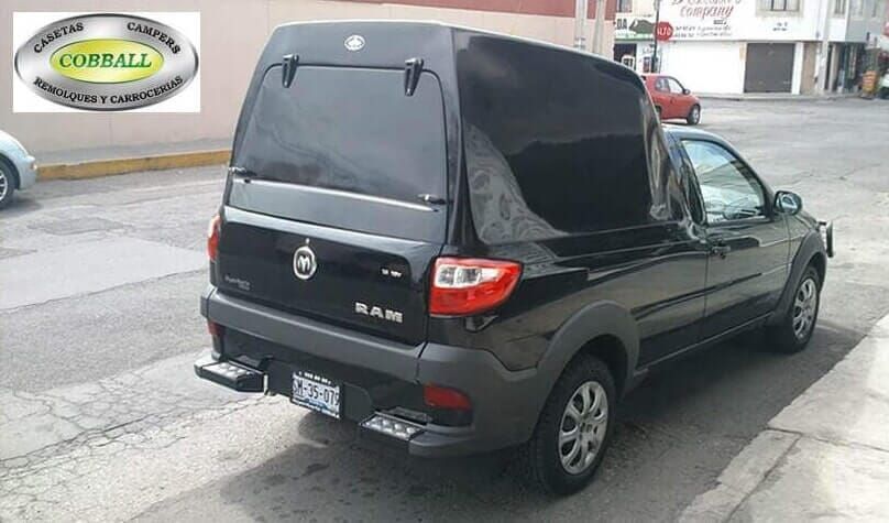 Camioneta RAM 700 negra con una gran cubierta de carga negra estacionada en una calle de la ciudad.