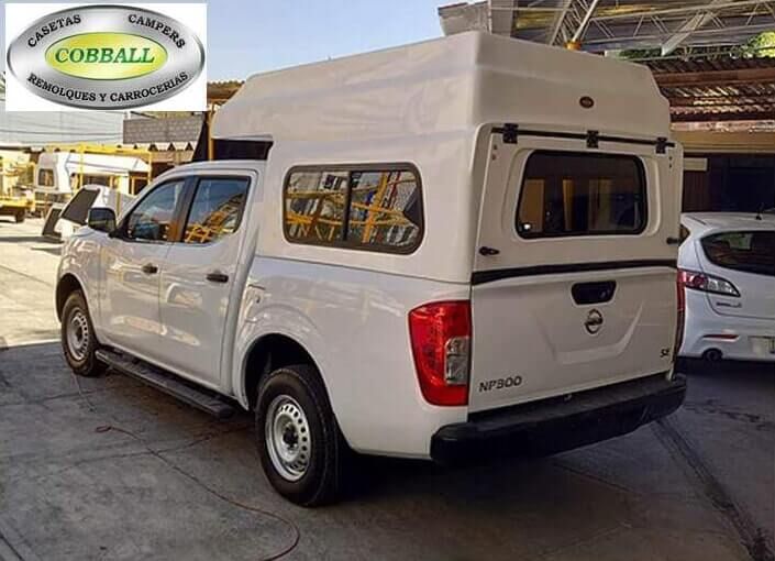 Camioneta Nissan blanca con una cubierta de fibra de vidrio blanca para la caja, estacionada en un lote al aire libre, con el logotipo de COBBALL.