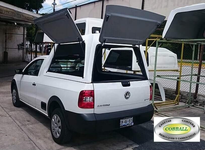 Camioneta Volkswagen Saveiro blanca con puertas laterales y traseras abiertas en un taller, con el logotipo de Cosball superpuesto.