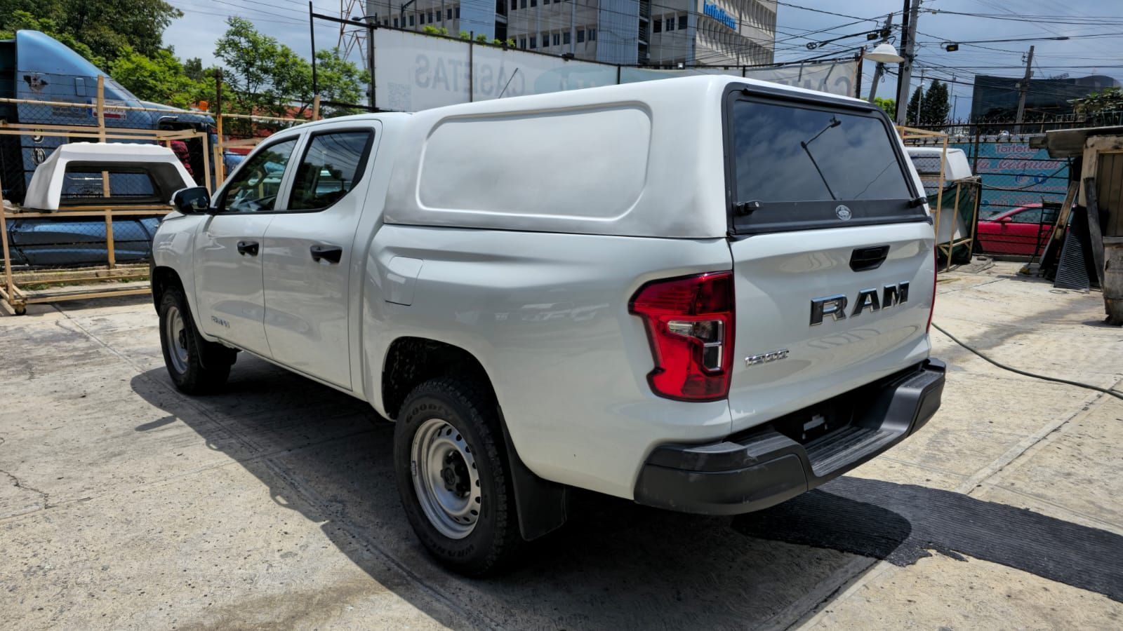 Camioneta Ram 700 blanca con una cubierta para la caja de carga blanca estacionada en un lote al aire libre en un día soleado.