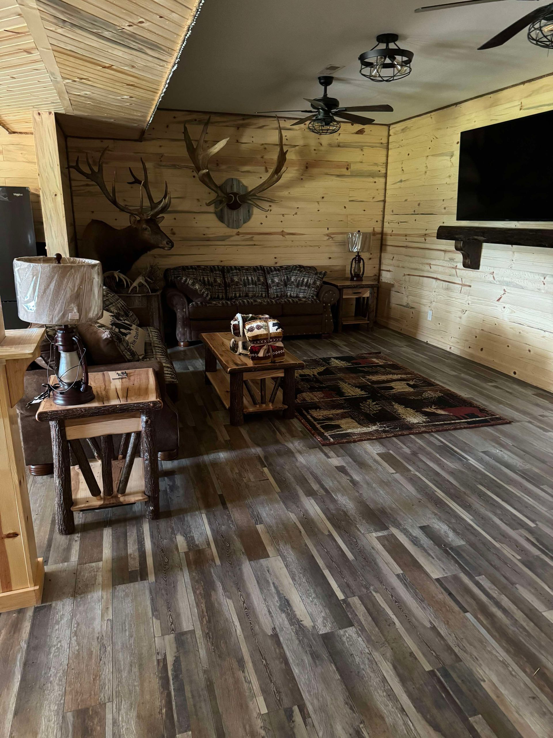 A living room with a couch , chairs , coffee table and television.