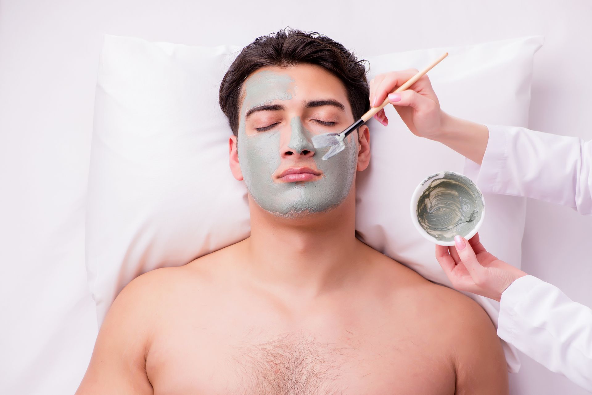 A man is getting a facial mask at a spa.