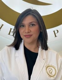 a woman in a white lab coat is standing in front of a sign .