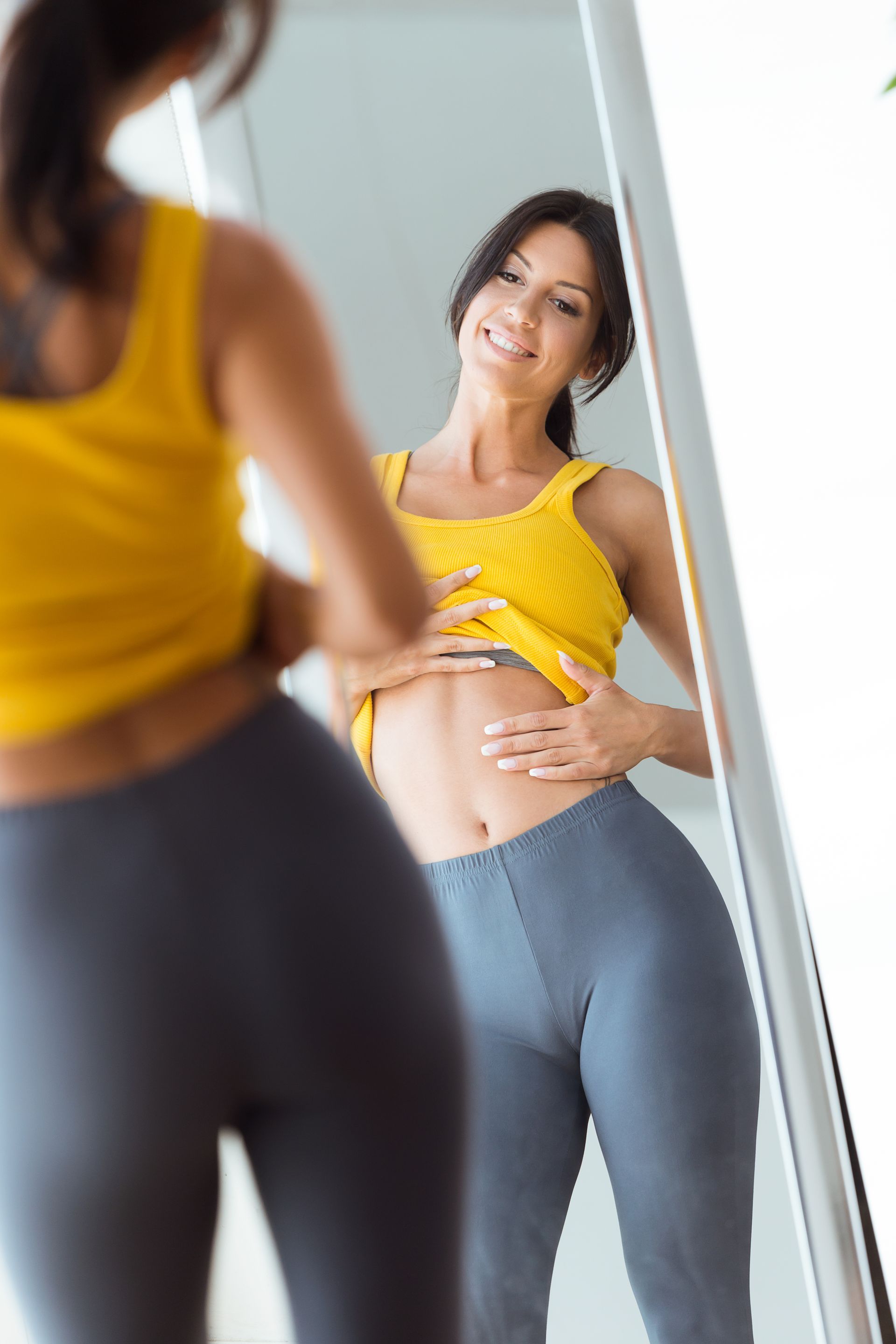 a woman is looking at her stomach in a mirror .