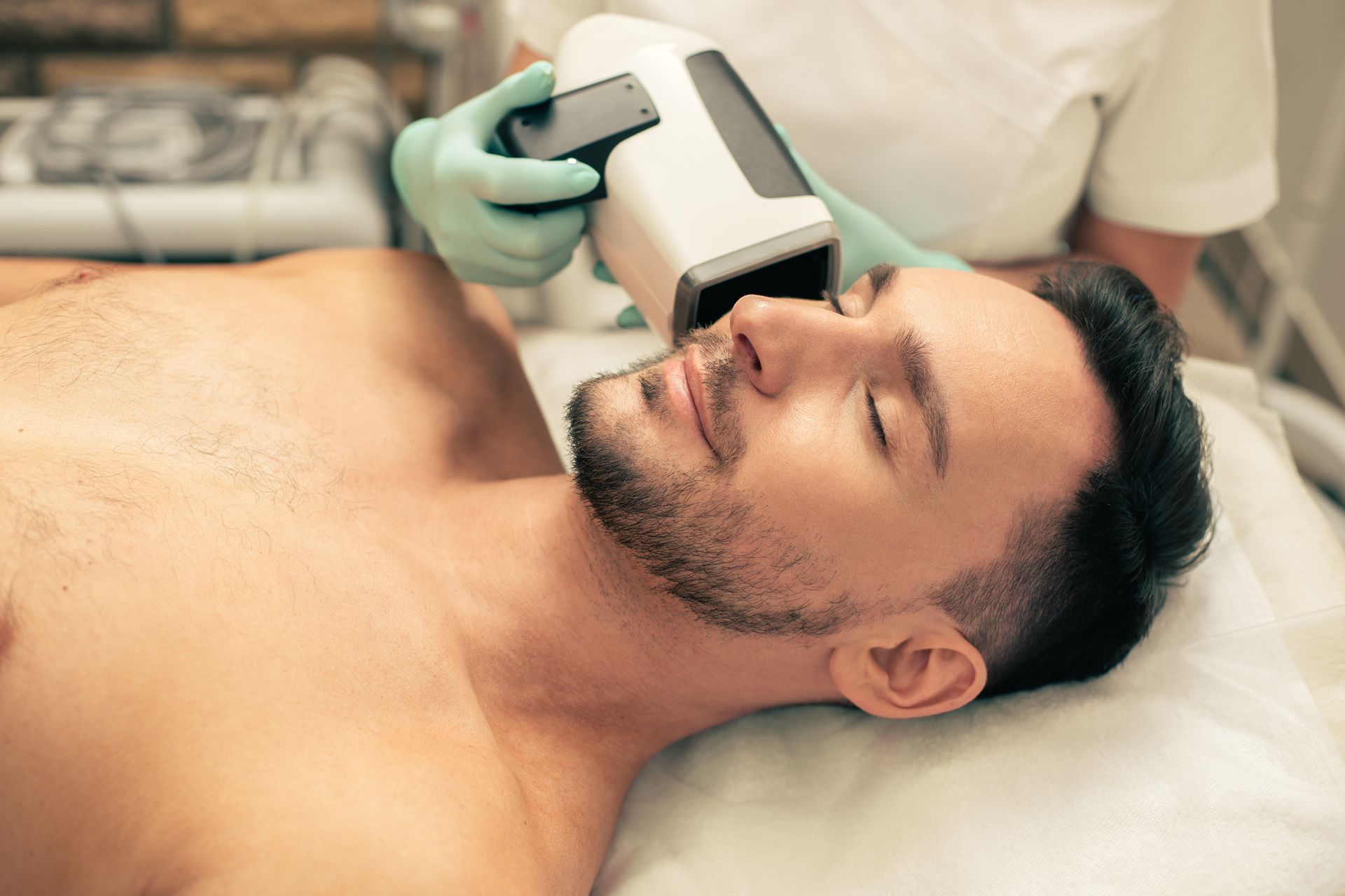 a shirtless man is getting a laser treatment on his face .