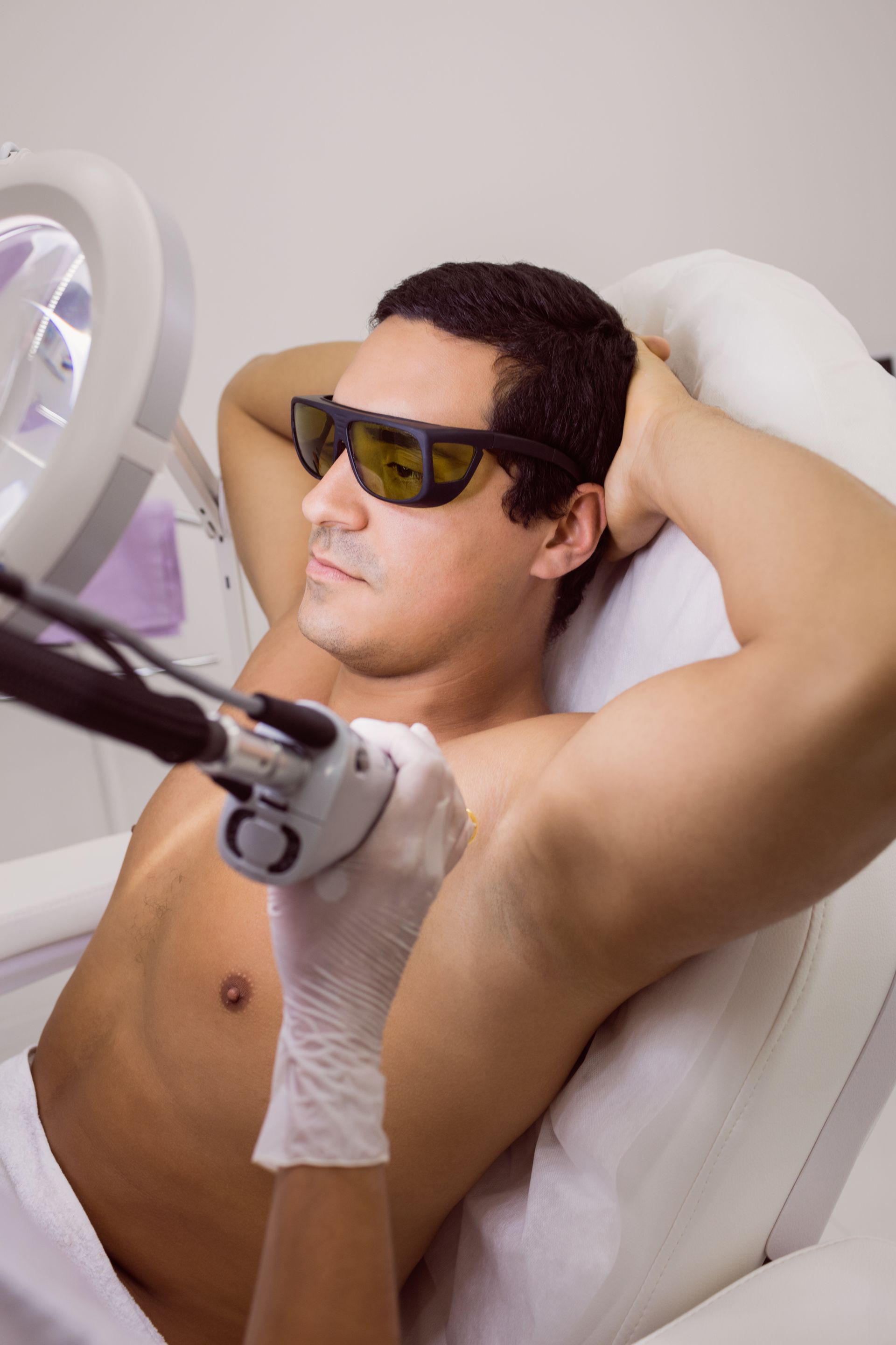 a shirtless man is getting a laser hair removal treatment on his armpits