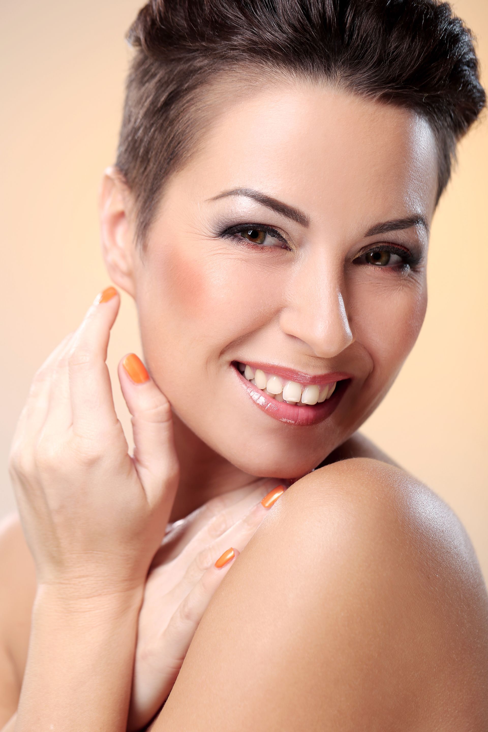 a woman with short hair is smiling and touching her face .