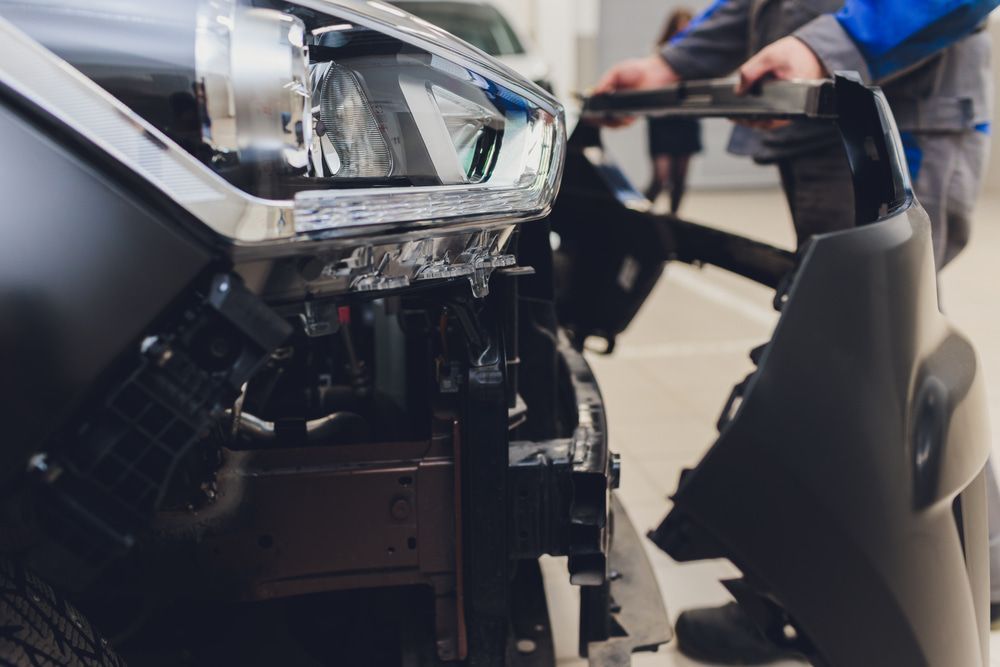 A Man Is Working On The Front Of A Car In A Garage — Taminda Smash Repairs In Gunnedah, NSW