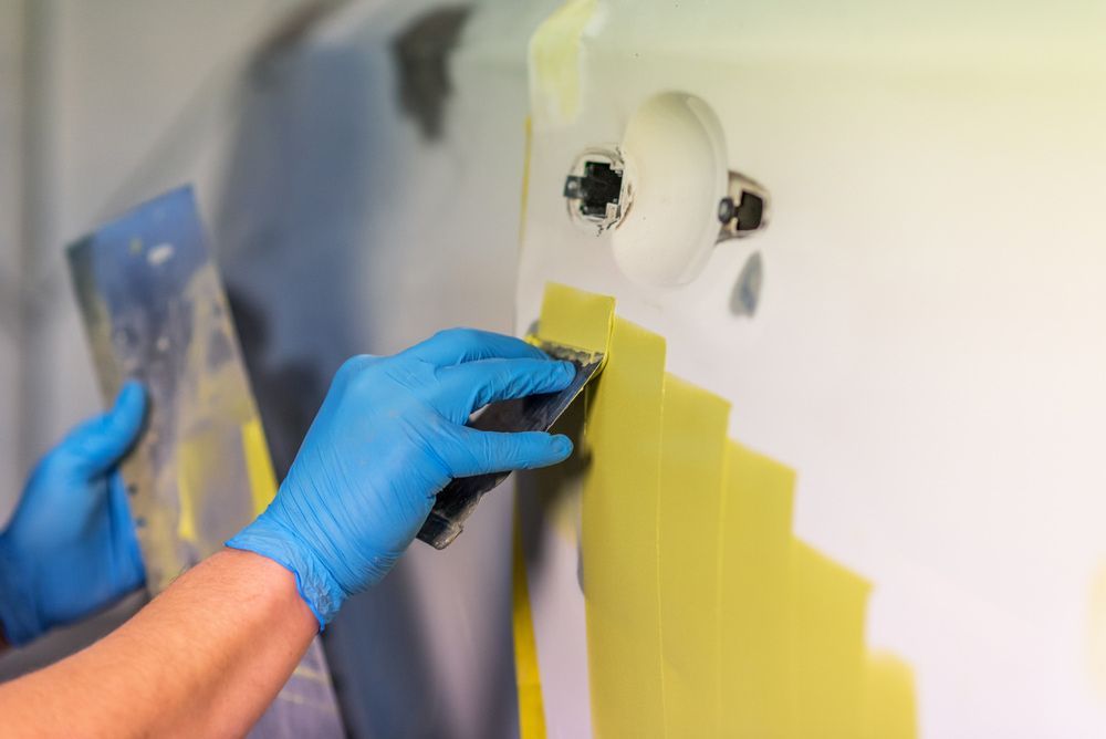 A Person Wearing Blue Gloves Is Sanding A Wall With A Sander — Taminda Smash Repairs In Walcha, NSW