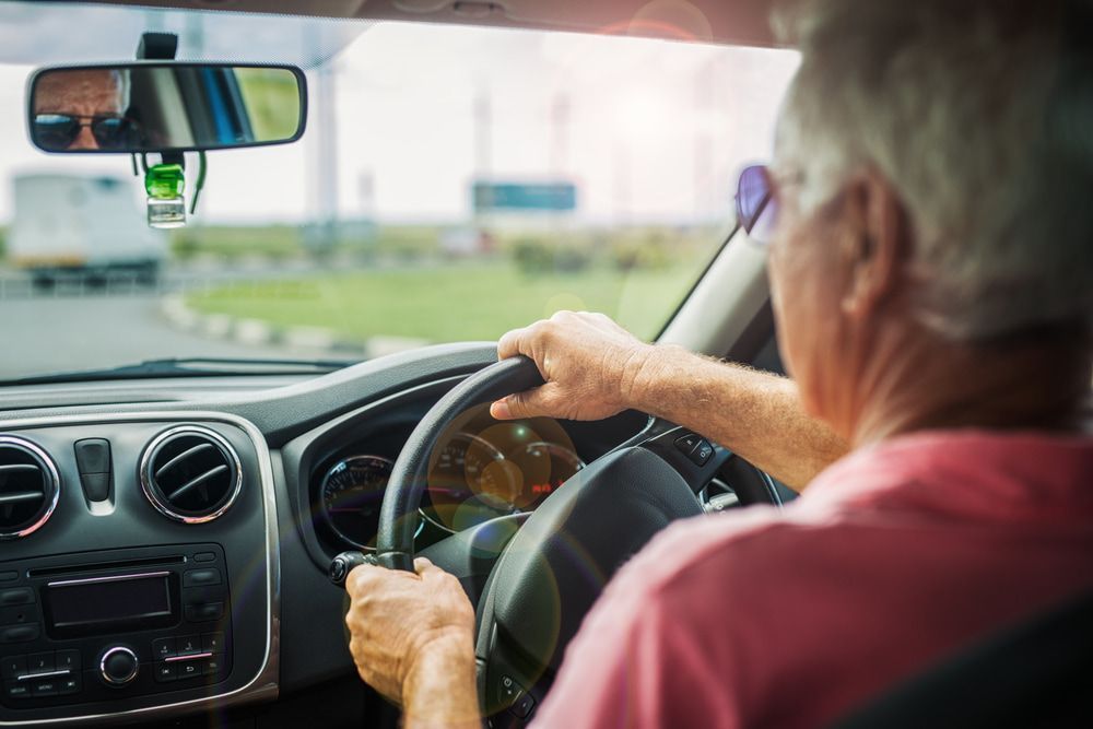 An Older Man Is Driving A Car On A Highway — Taminda Smash Repairs In Tamworth, NSW
