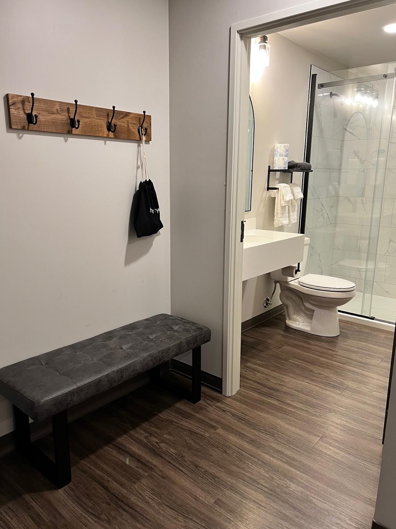 Bathroom entry with bench, coat rack, and partially visible shower stall.