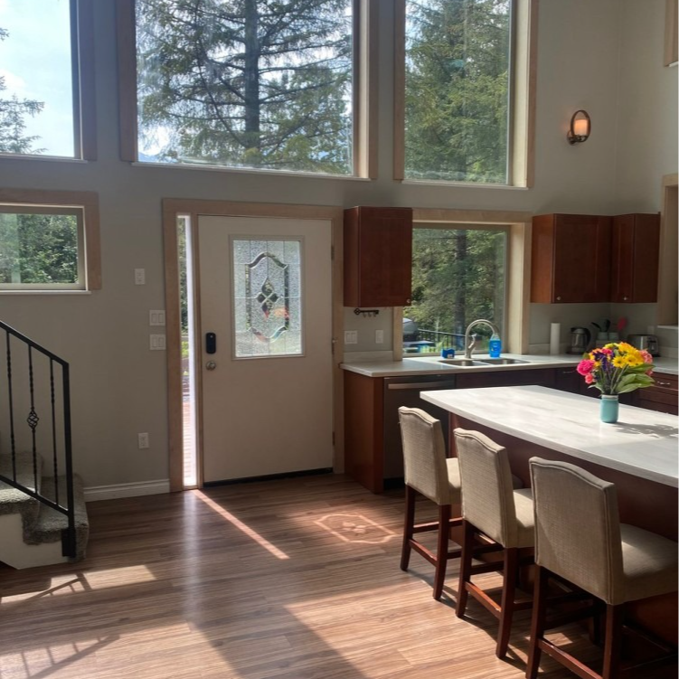 Kitchen interior with windows, open door, and breakfast bar with stools.