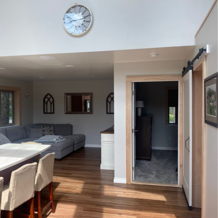 Open-concept living space with a kitchen, living room, and a door leading to a room.