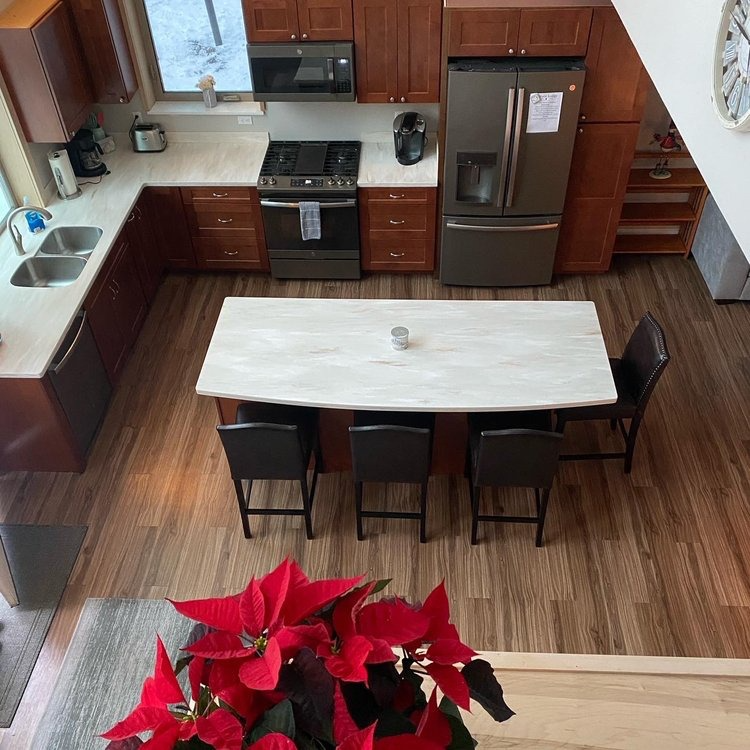 High-angle view of a kitchen with dark cabinets, white countertops, a stainless steel fridge.
