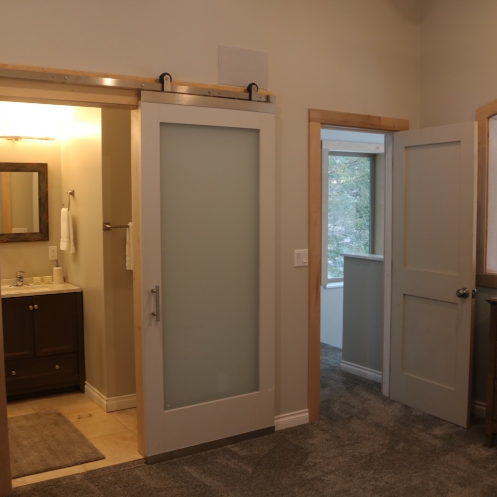 Interior with open doors: bathroom with vanity, frosted glass sliding door, and another door to outside.