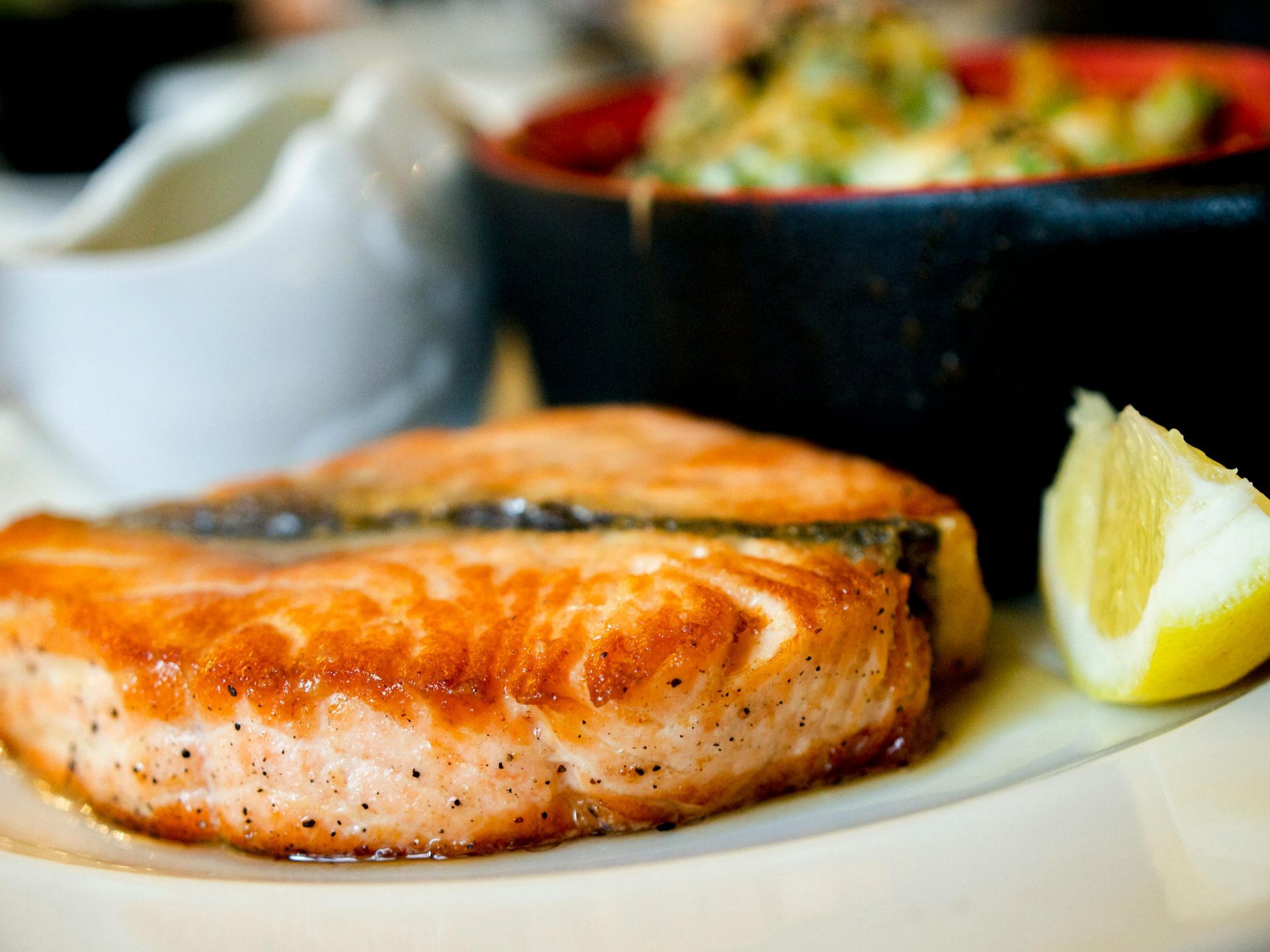 Grilled salmon fillet with a lemon wedge and a side dish.