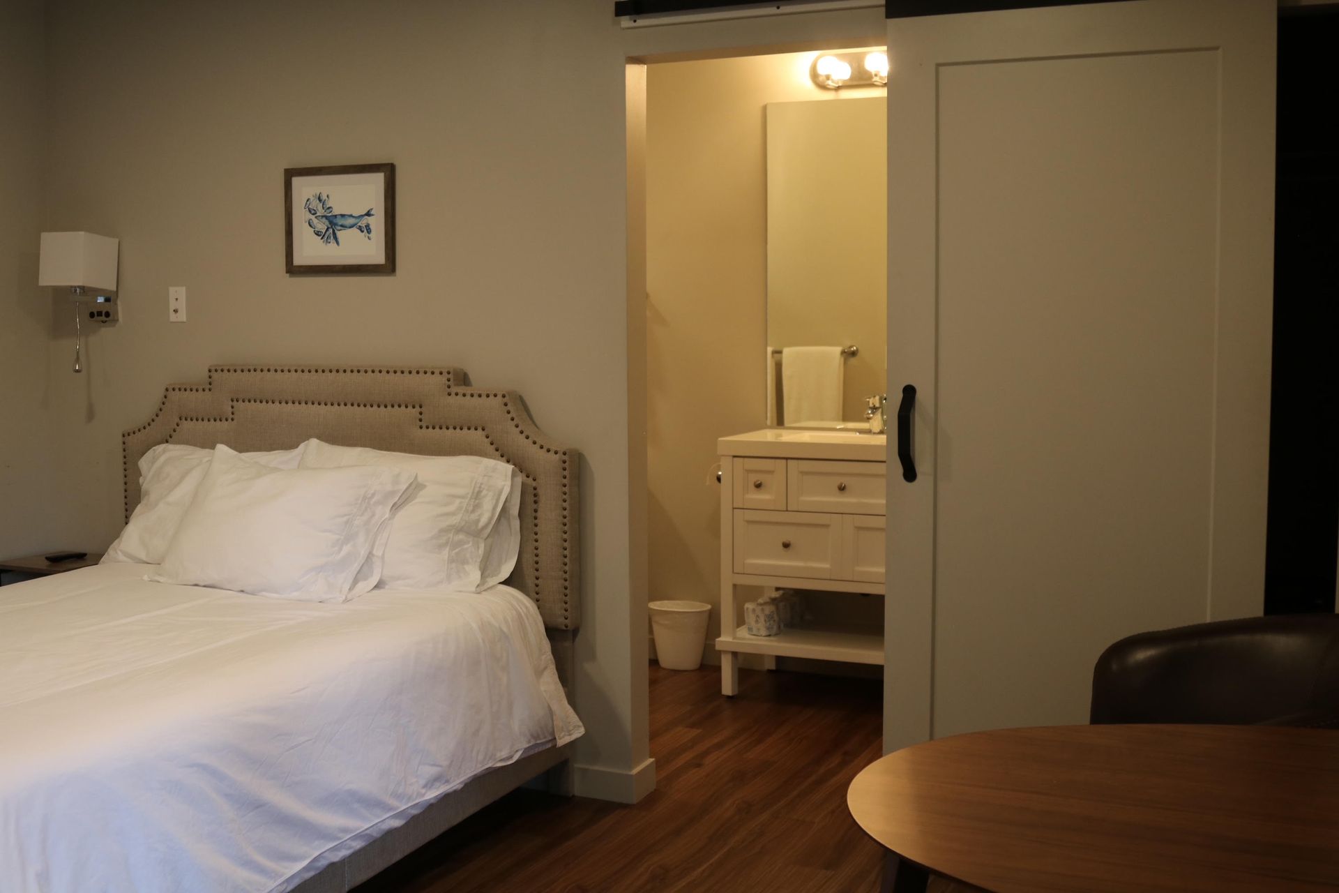Bedroom with bed, bathroom visible, and wooden table in front.