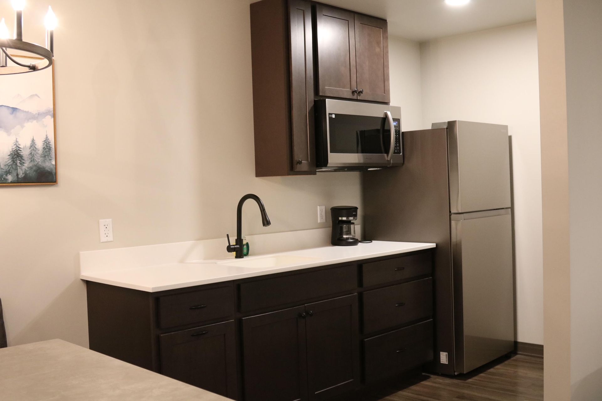 Small kitchen with brown cabinets, white countertop, stainless steel appliances.
